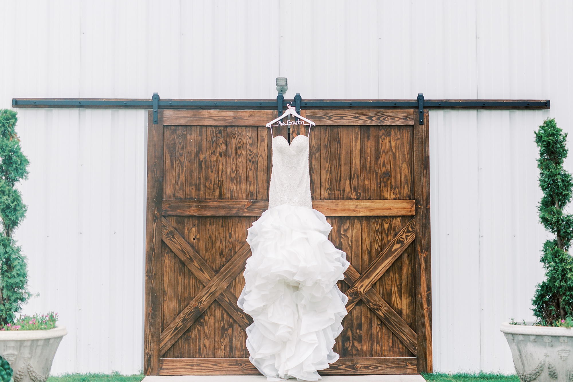mermaid wedding dress hangs on barn door at Belle's Venue