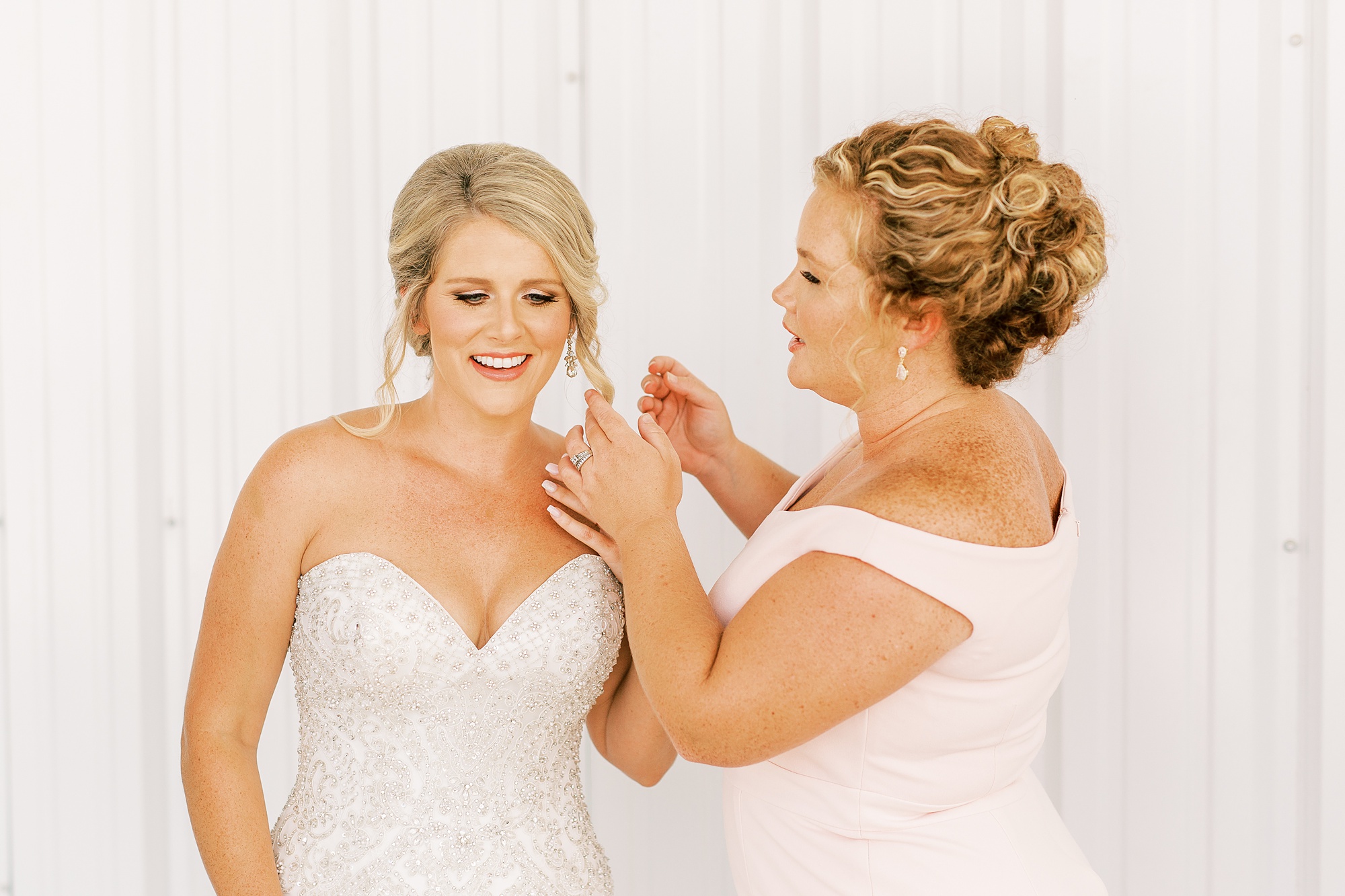 maid of honor helps bride with earrings