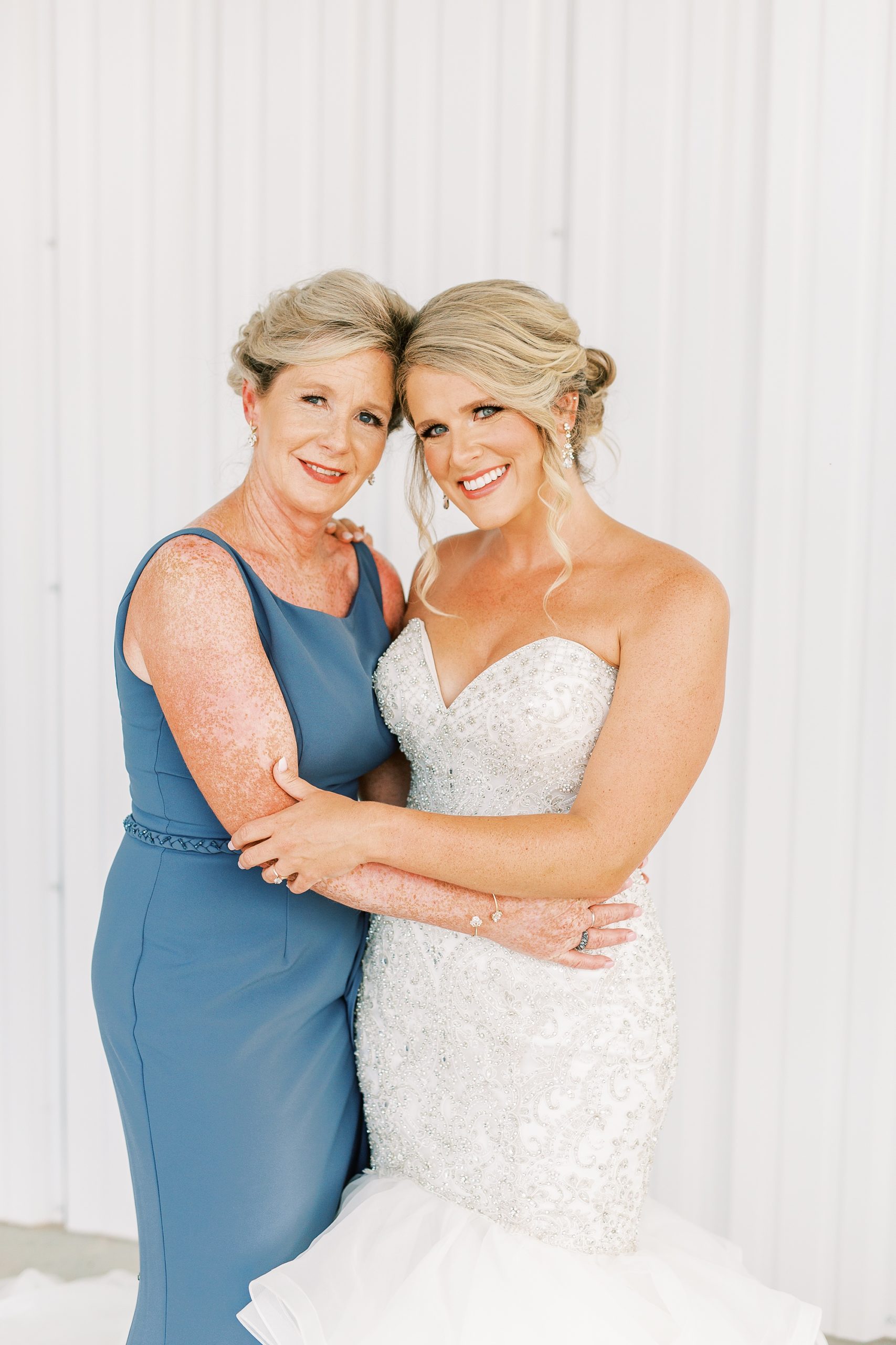 bride and mom pose together