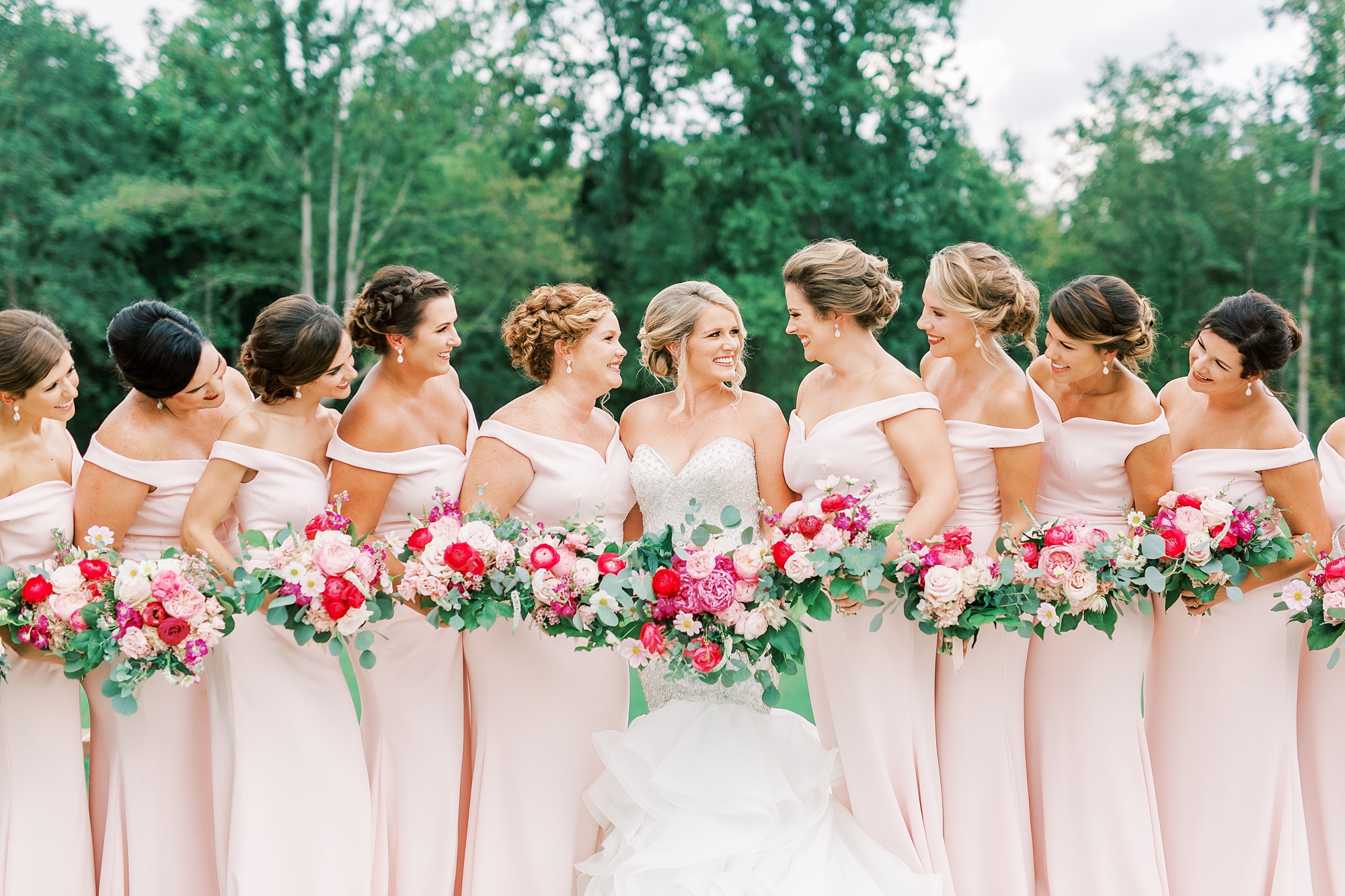 bridesmaids in pink dresses pose with bride