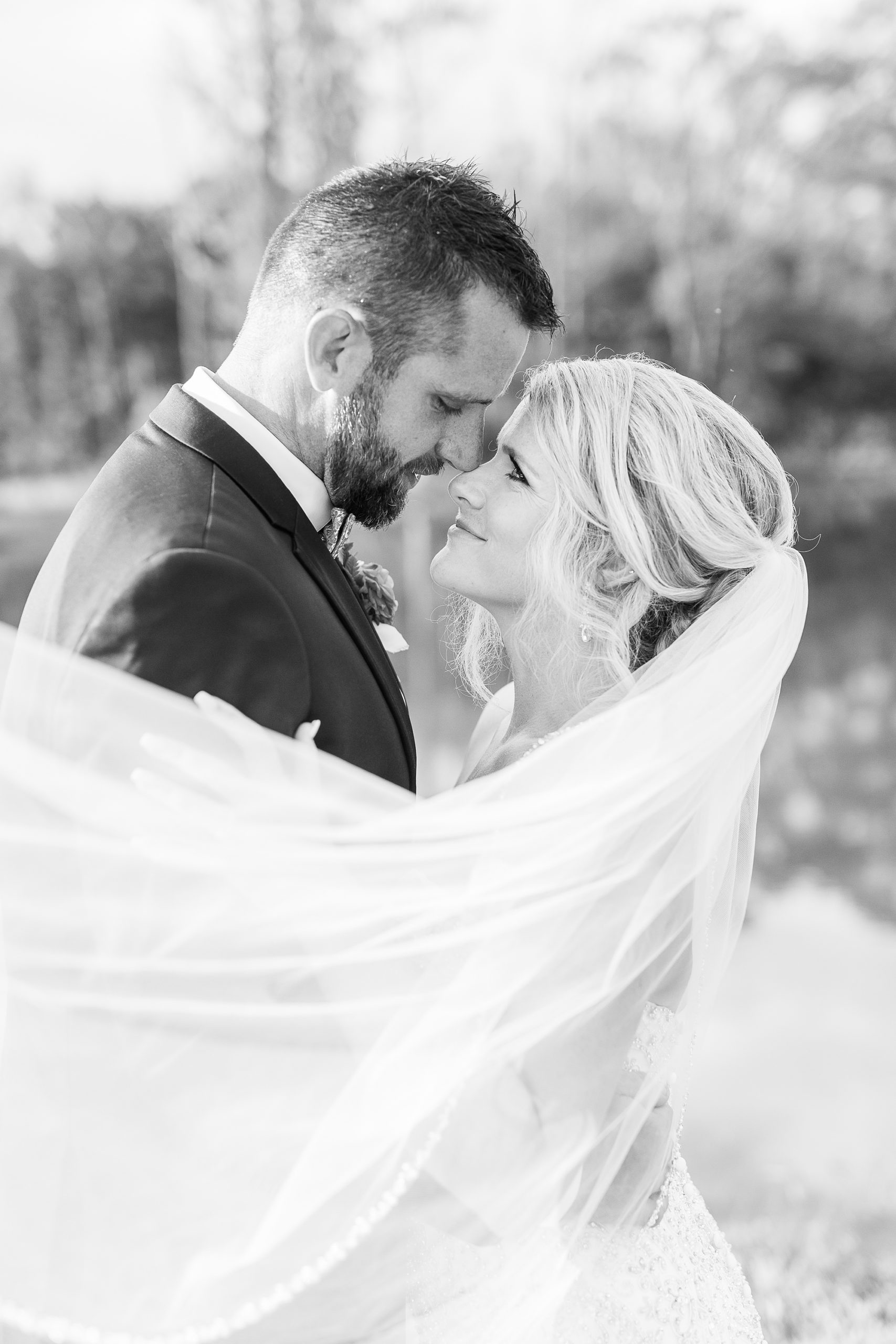 bride and groom smile at each other while veil wraps around them