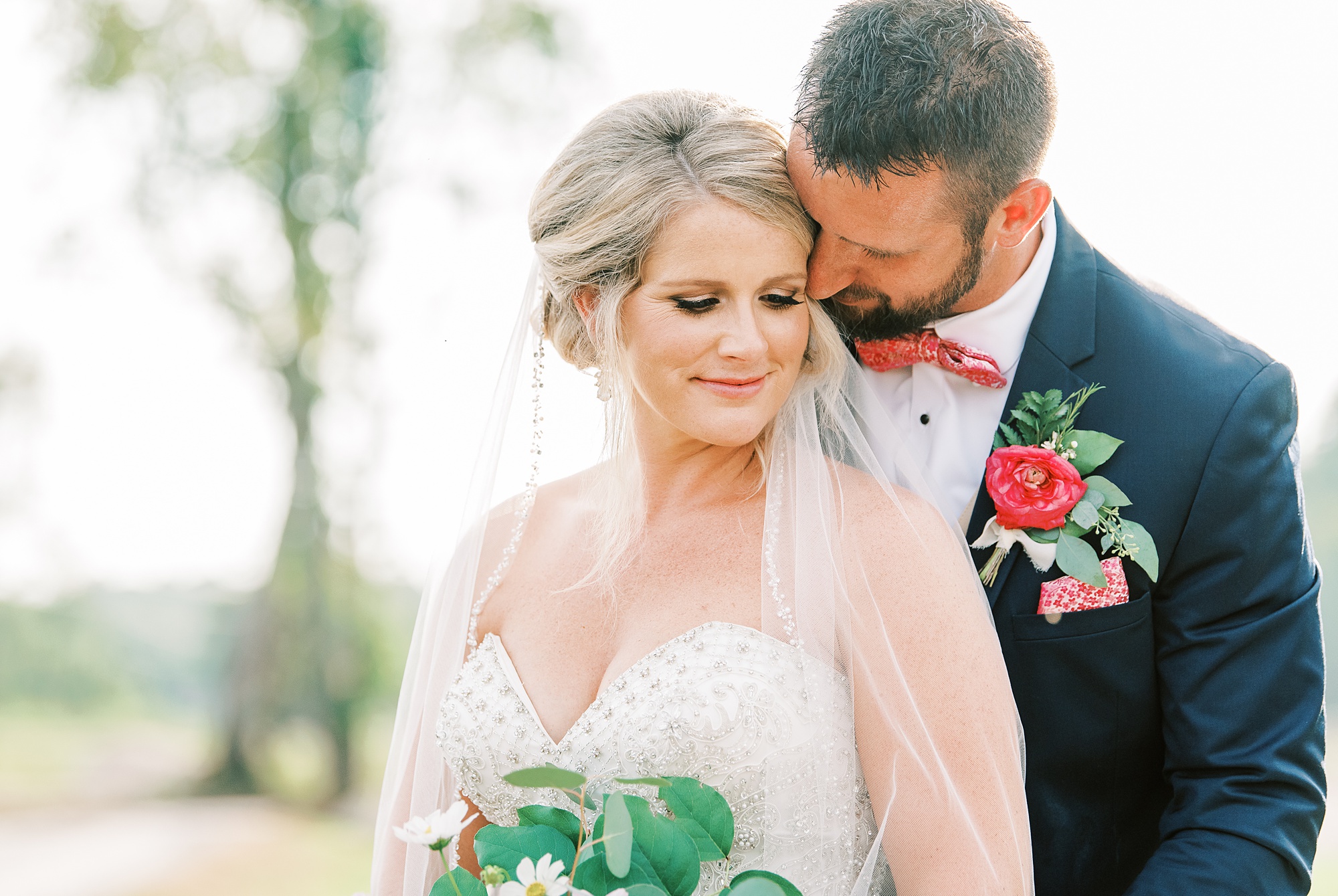 groom whispers in bride's ear during wedding photos