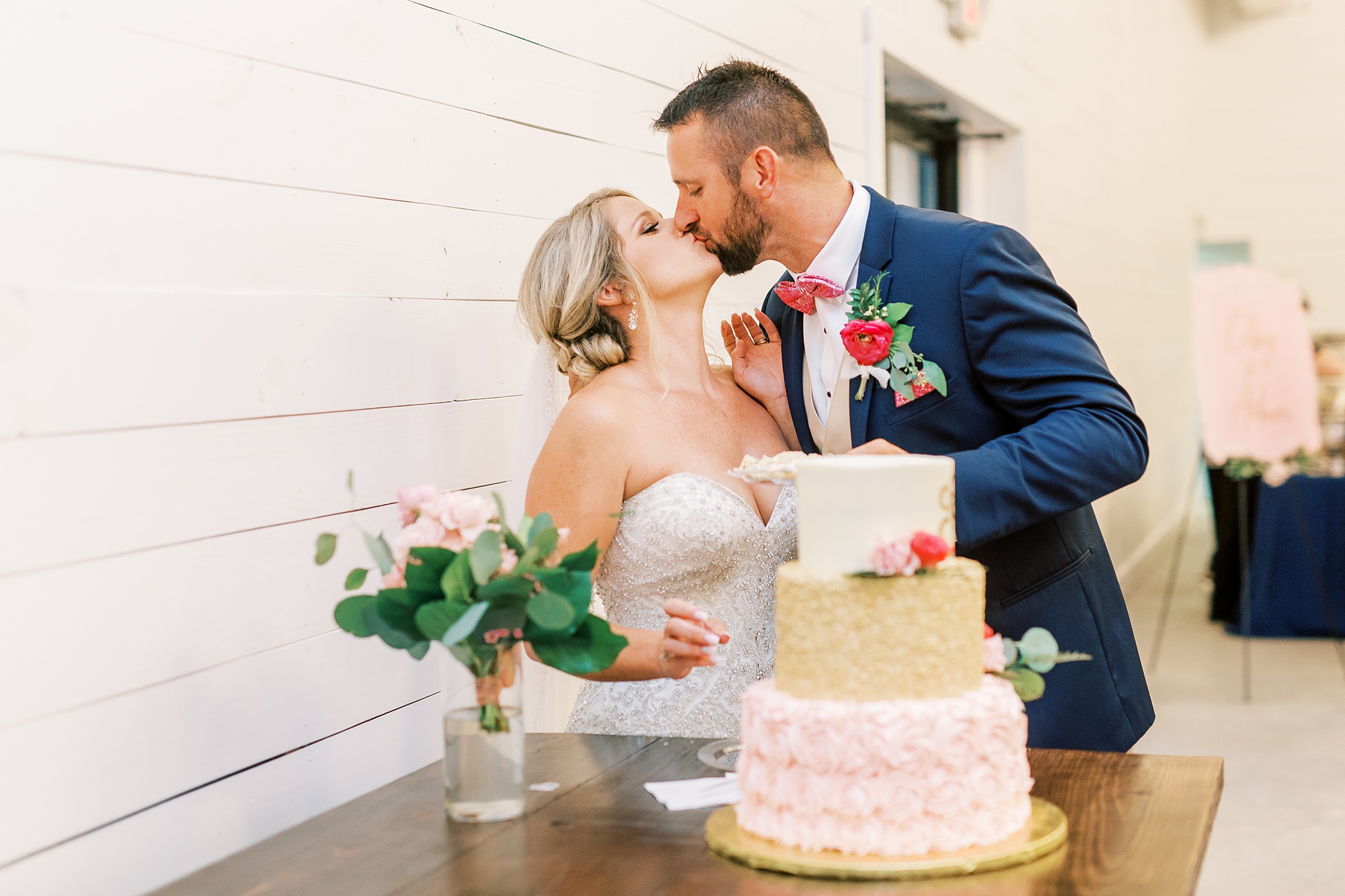 newlyweds kiss after cutting wedding cake