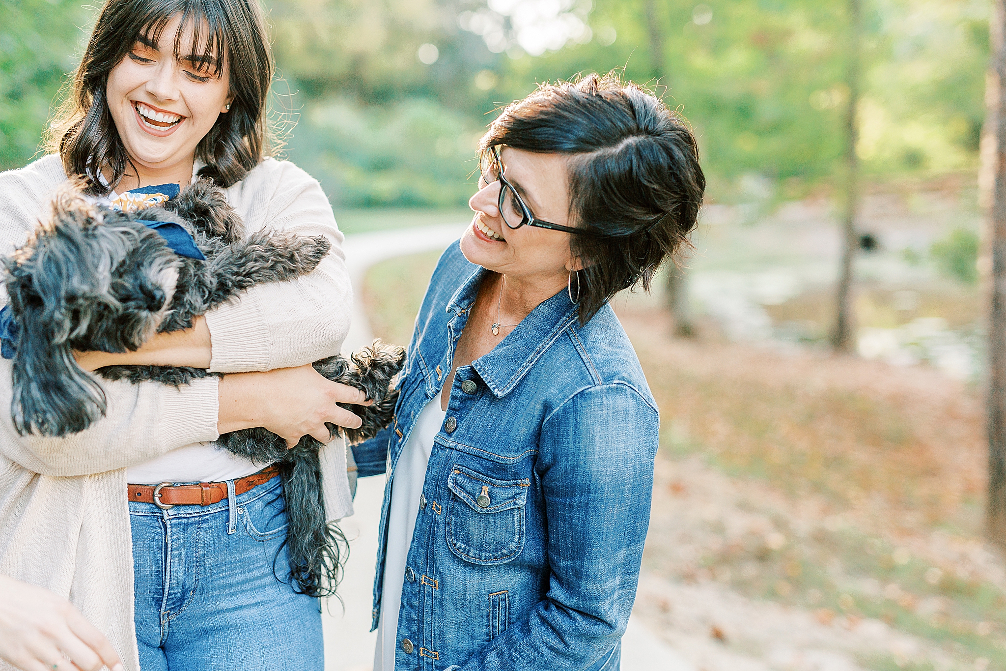 mom looks at small dog in daughter's arms