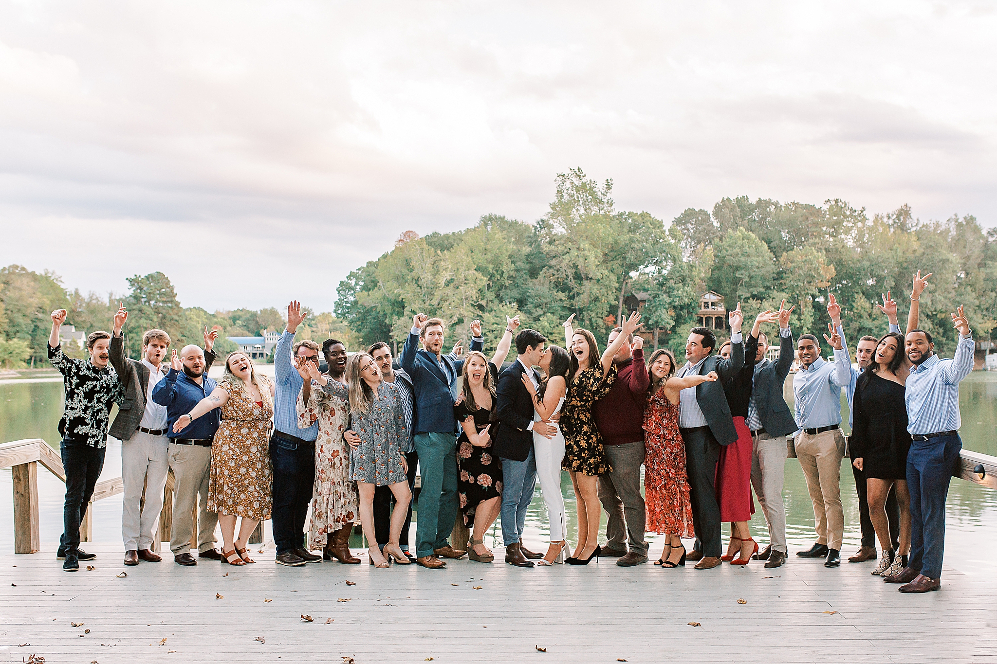 bride and groom pose with wedding party during welcome dinner at Lake Wylie