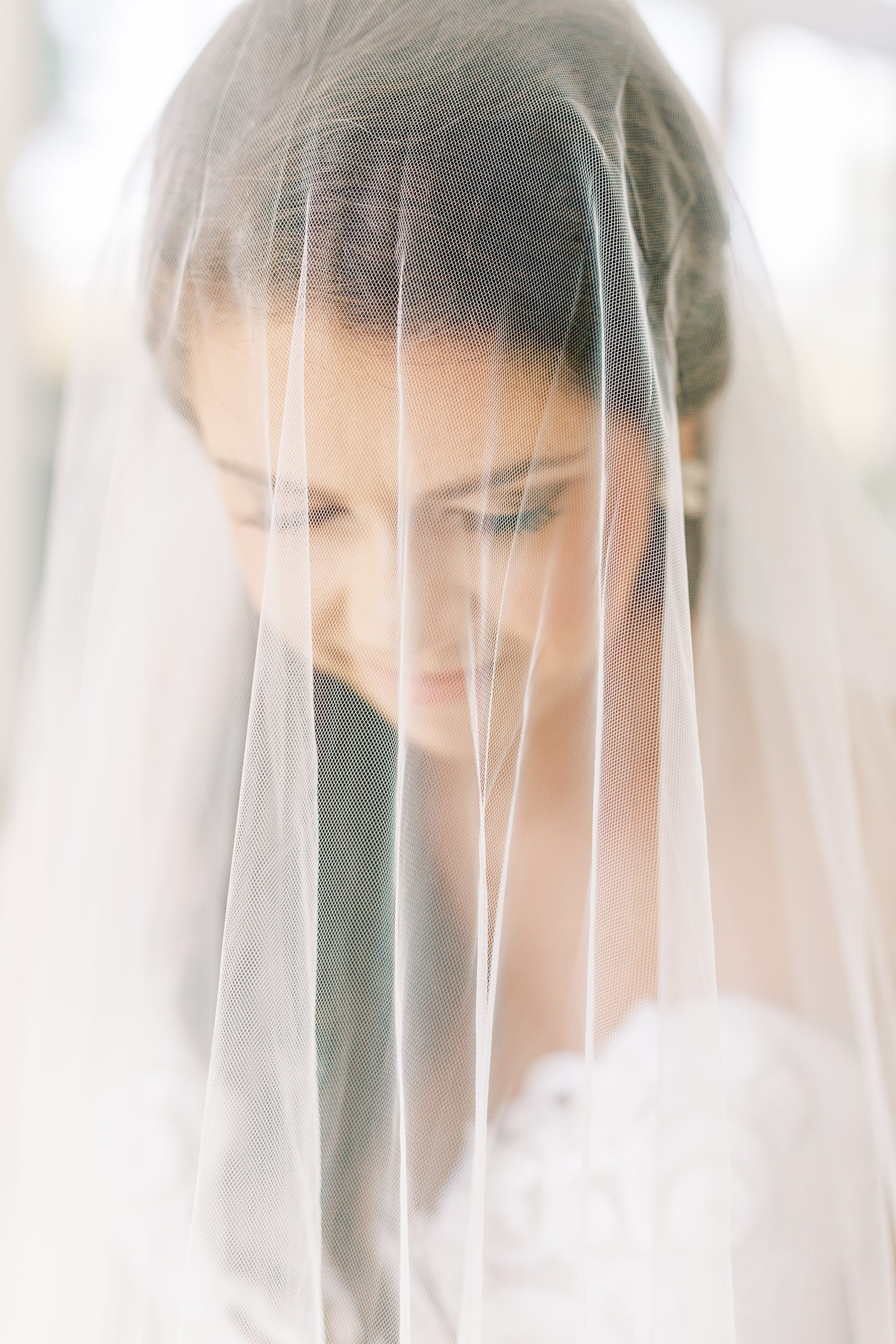 bride looks down with veil over her face