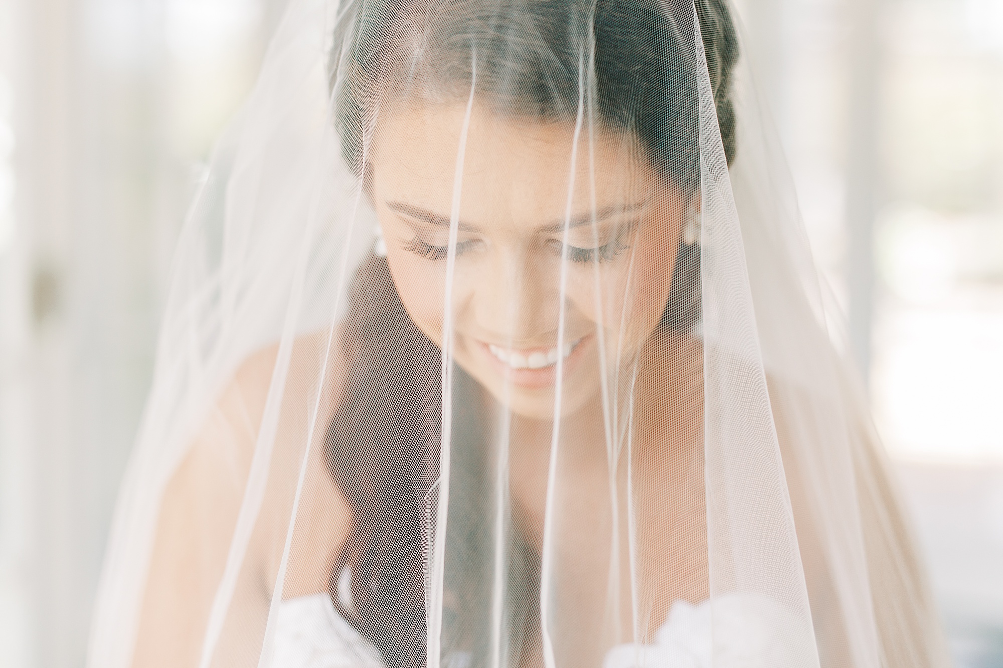 bride looks down at bouquet with veil over face