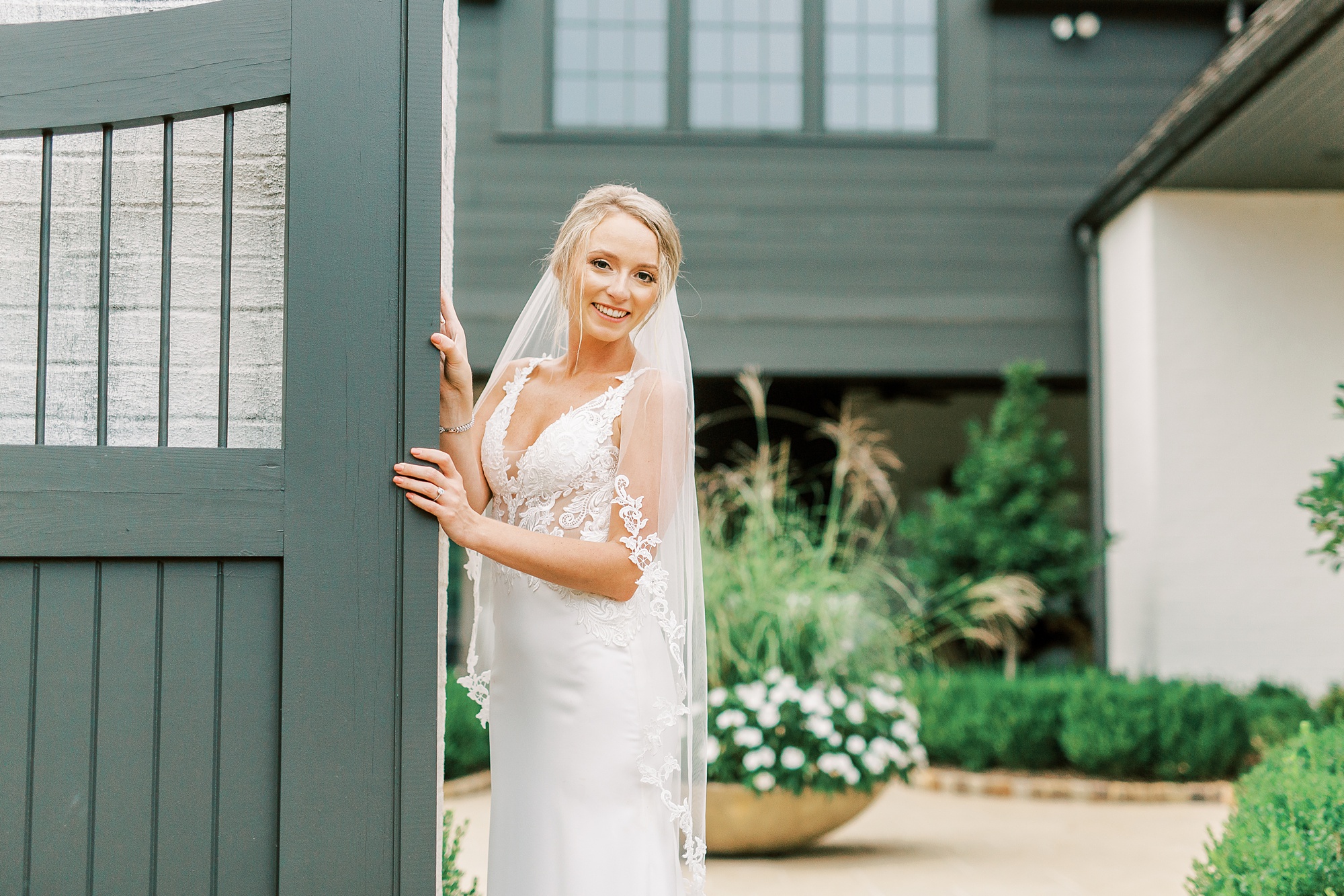 bride leans against gate at The Andrews Farm
