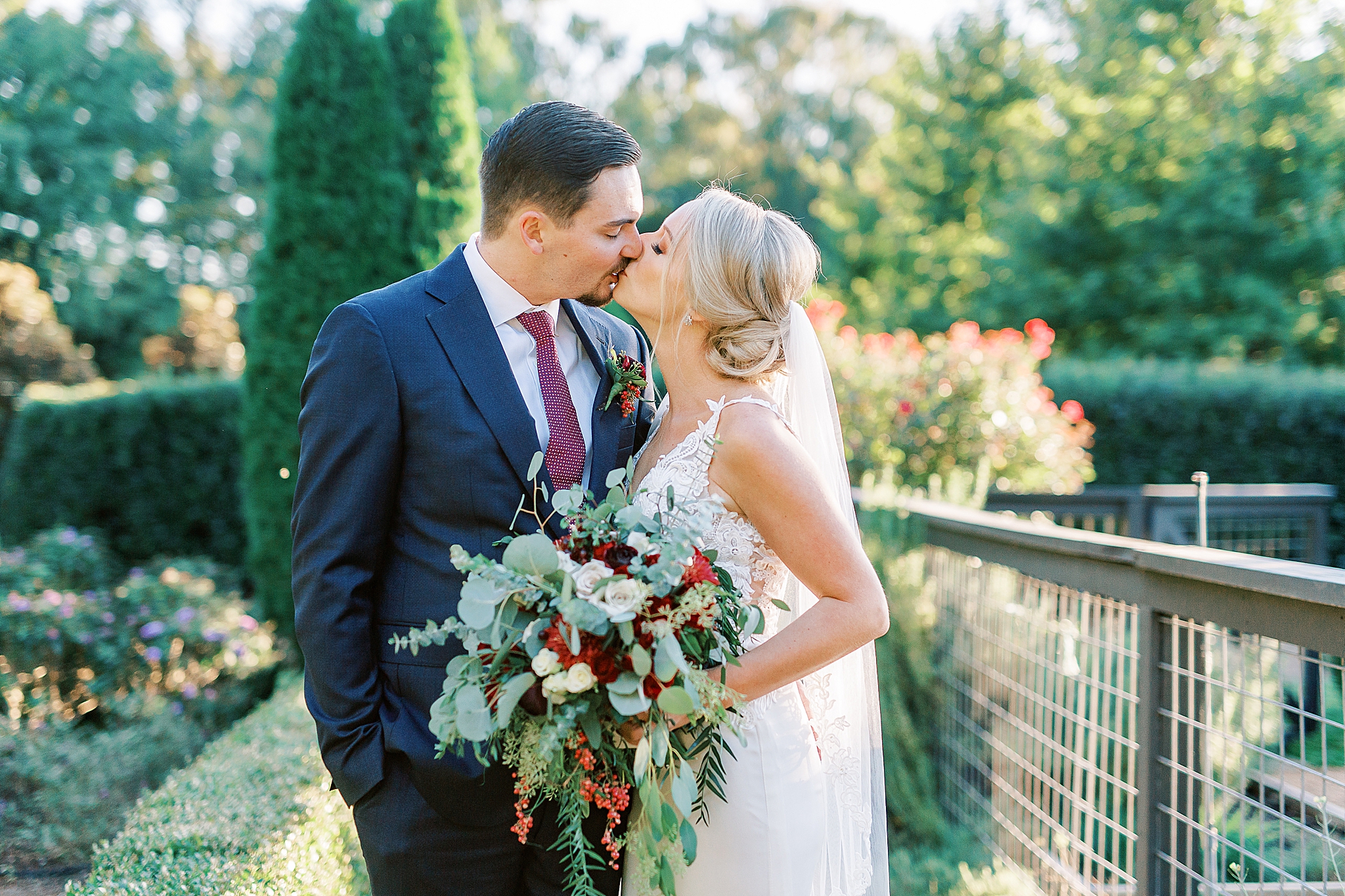 newlyweds kiss by gardens at The Andrews Farm