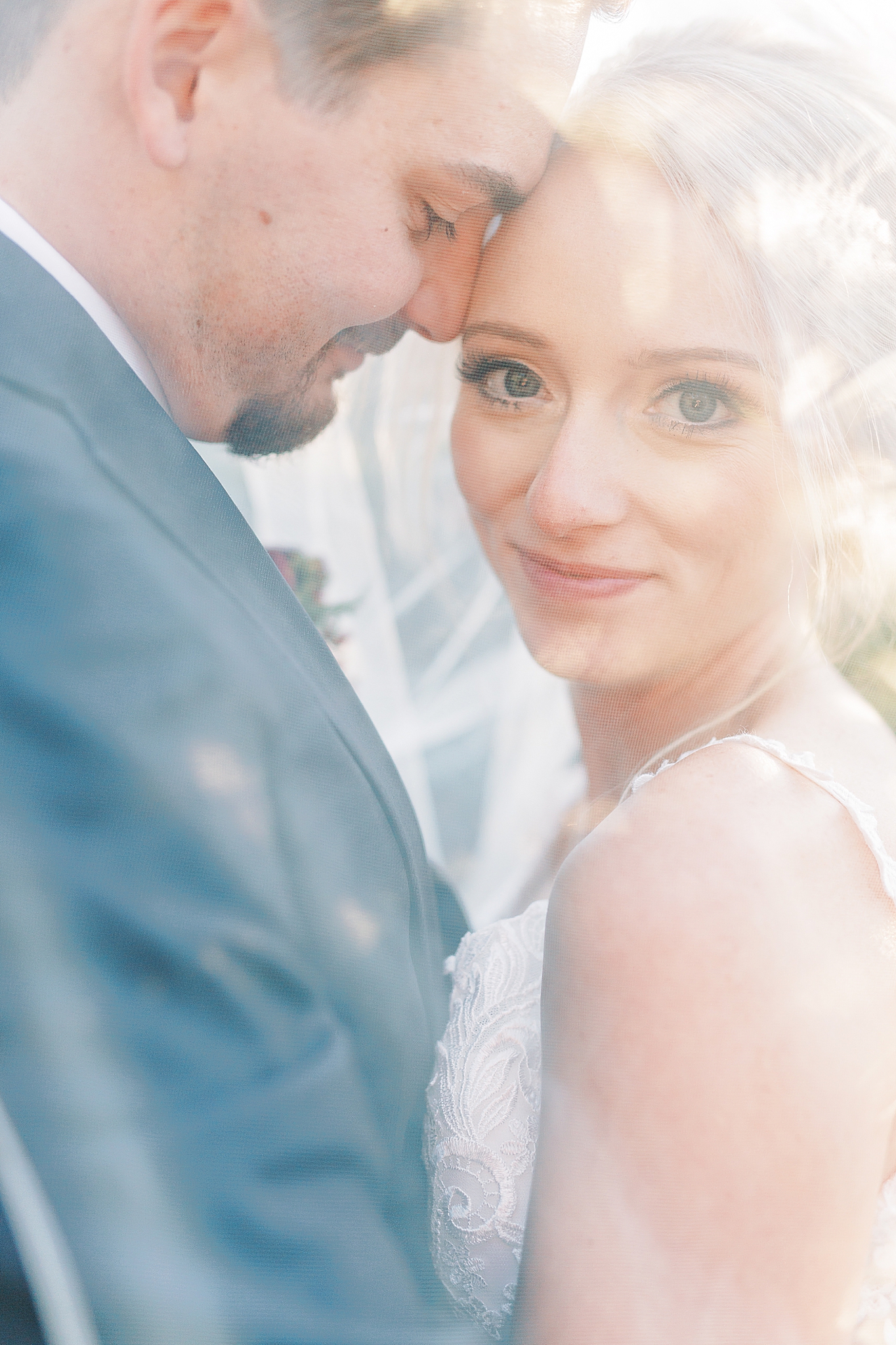 newlyweds pose under bride's veil