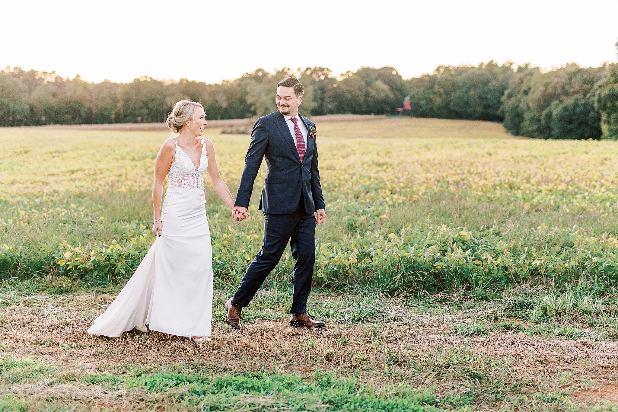 bride and groom walk along field at The Andrews Farm
