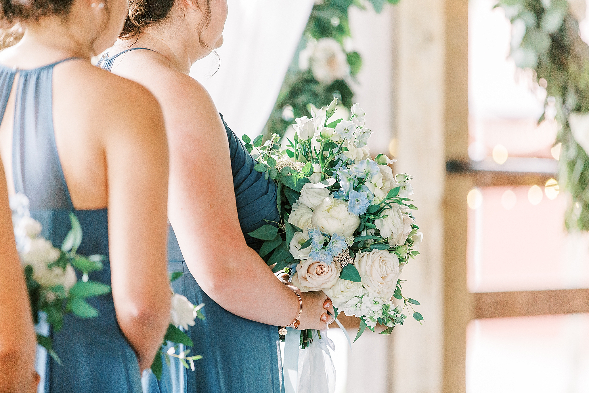 bridesmaid holds bouquet with white and blue flowers