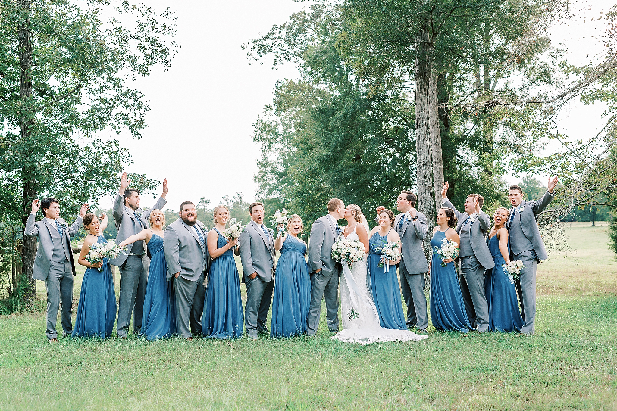 bride and groom kiss with bridal party around them