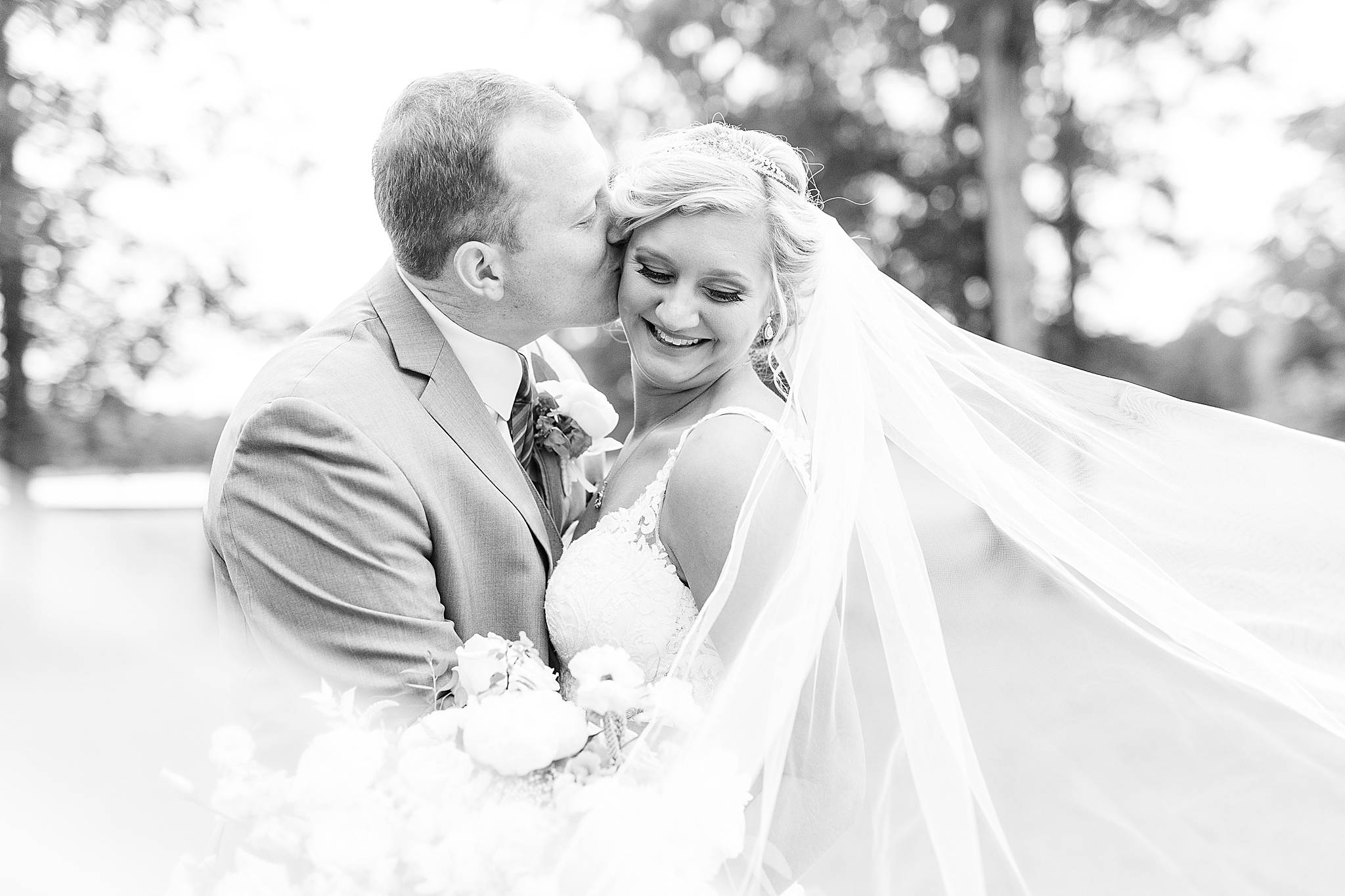 black and white portrait of bride and groom with veil floating