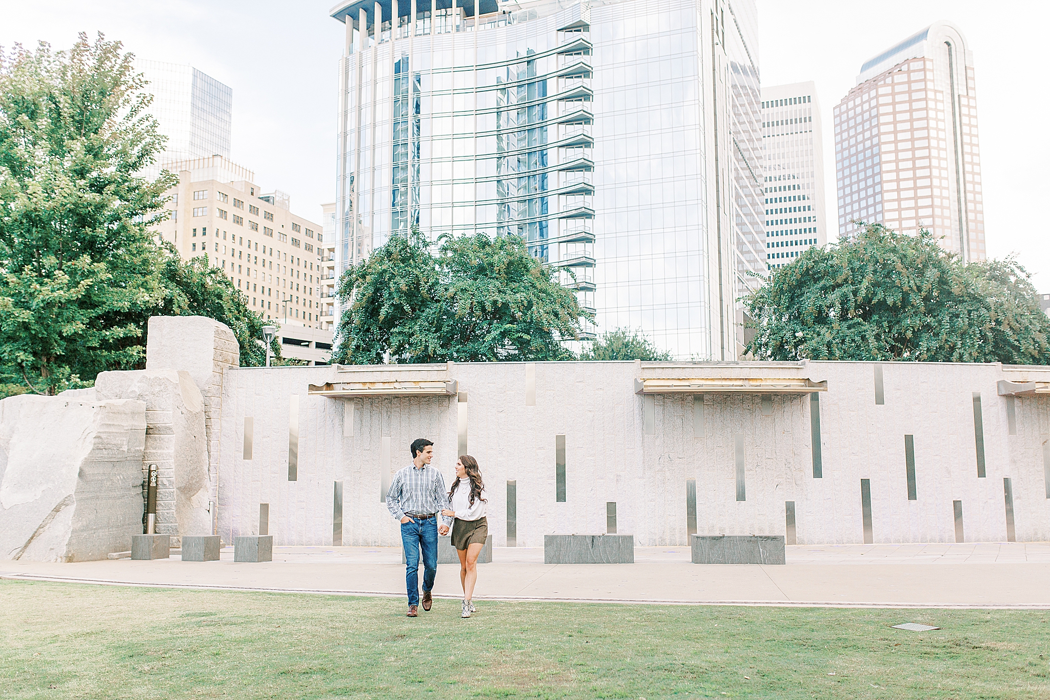 bride and groom pose in Romare Bearden Park in front of city skyline