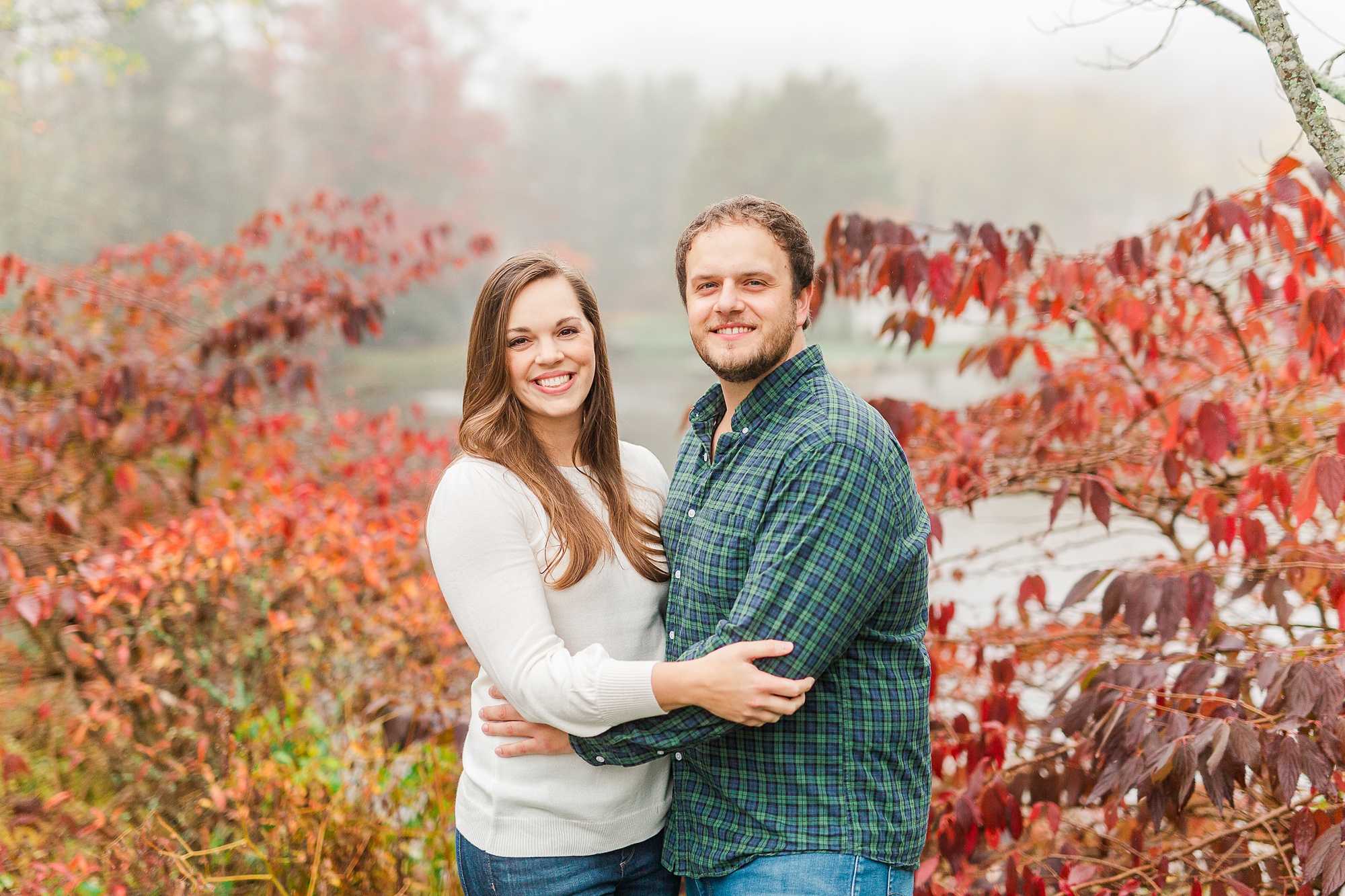 engaged couple poses by red tree during Blowing Rock engagement photos
