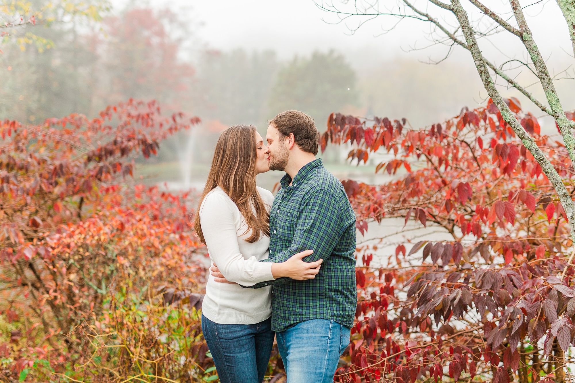 engaged couple kisses by red trees in NC