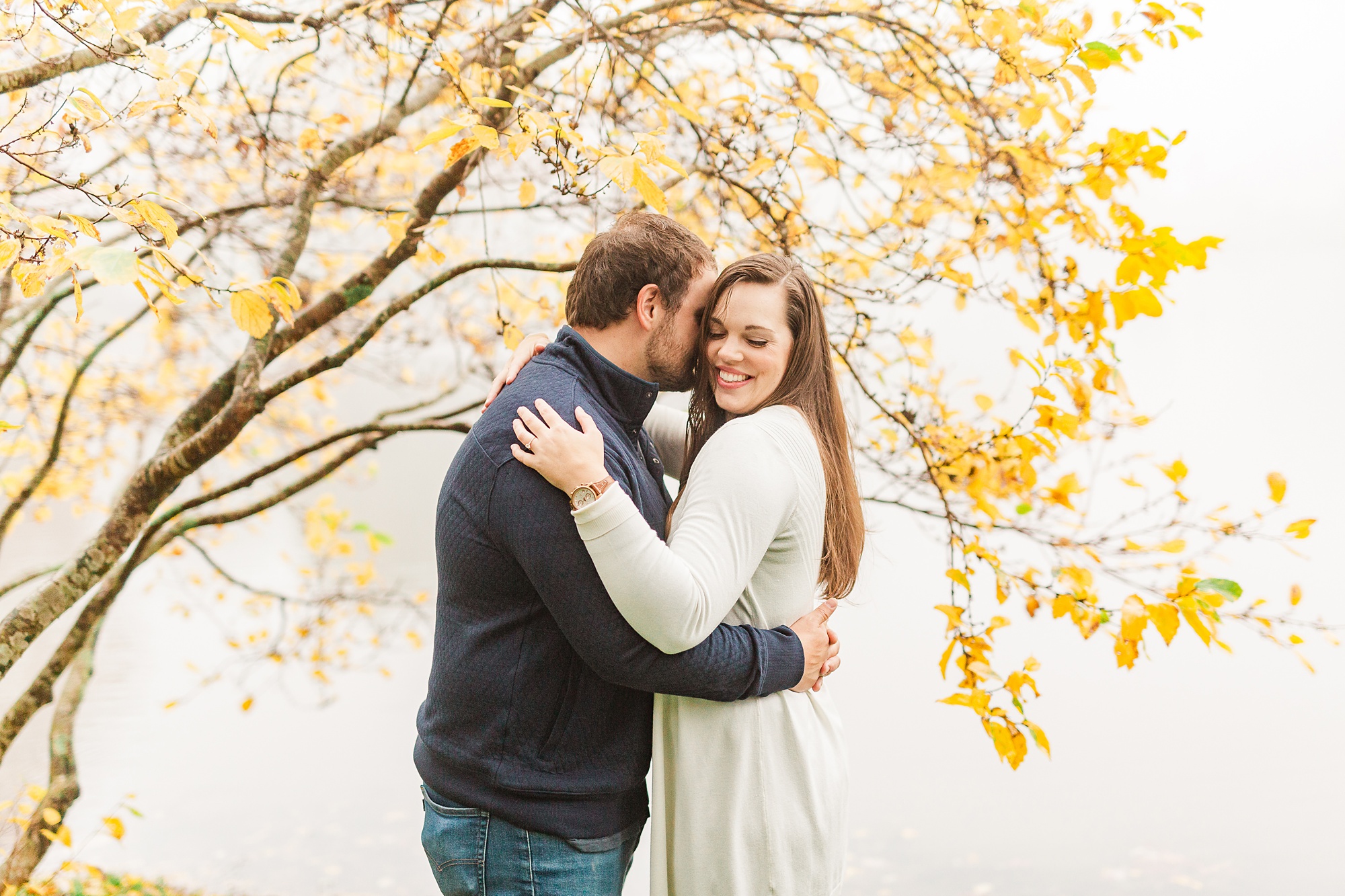 groom whispers in bride's ear during Blowing Rock engagement photos