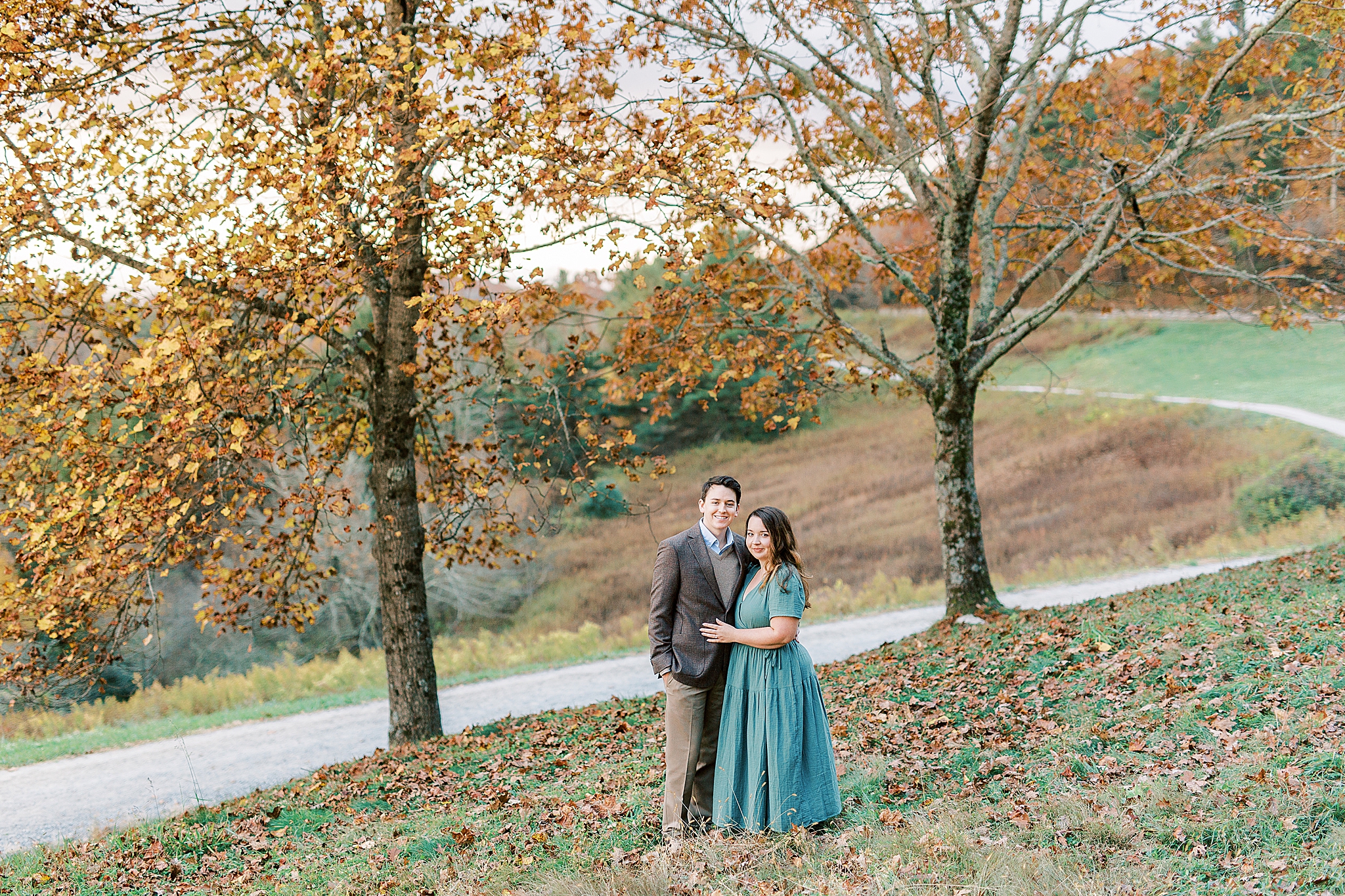 couple poses by tree for fall engagement portraits