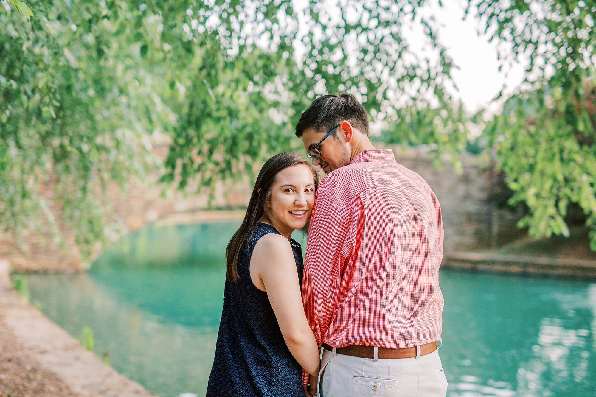 bride leans against groom during summer engagement session at Freedom Park