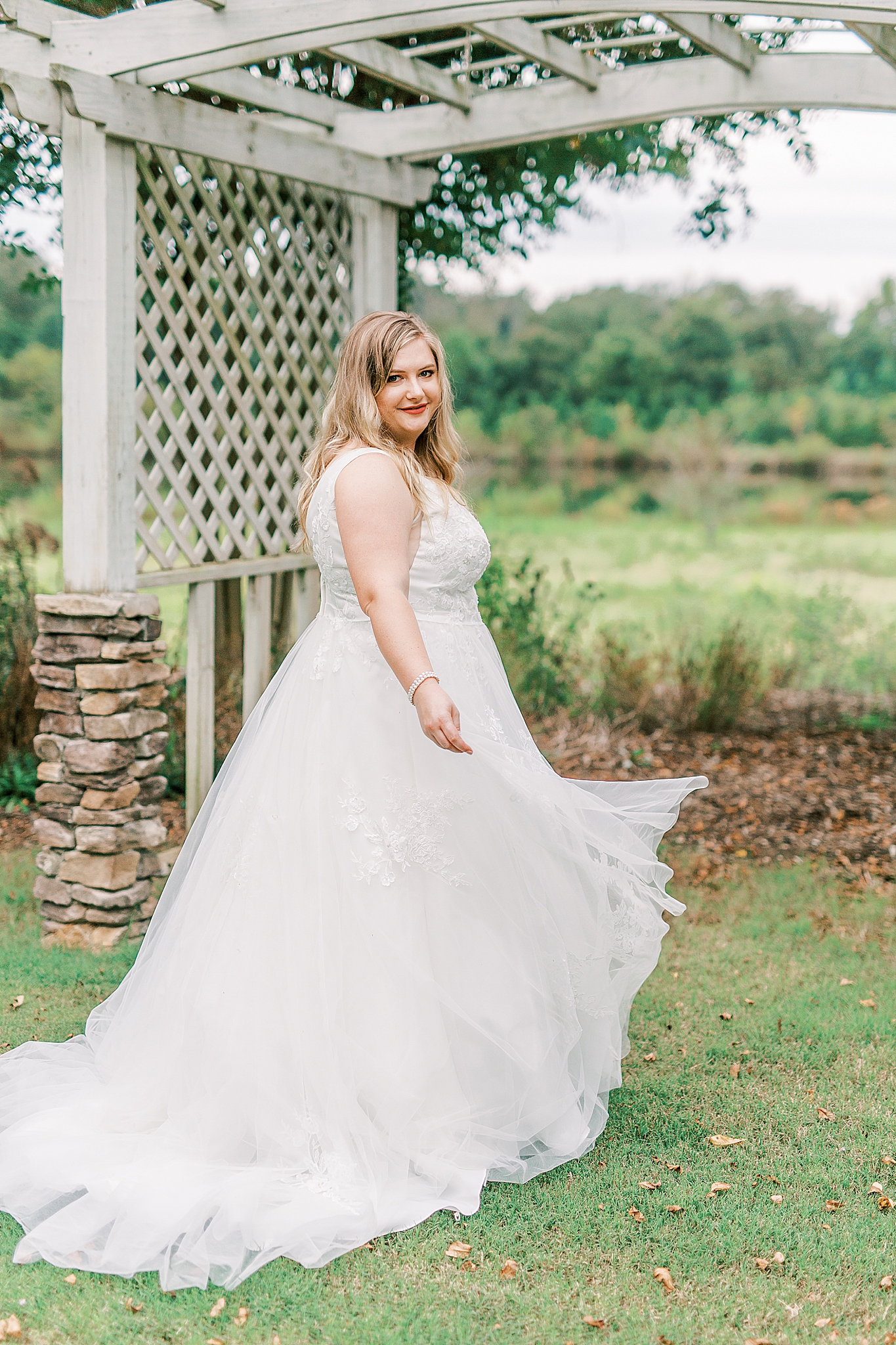 bride twirls in wedding gown under wooden arbor
