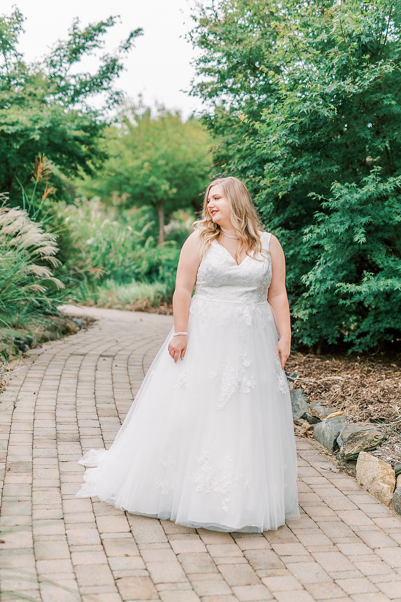 bride walks through gardens in wedding gown
