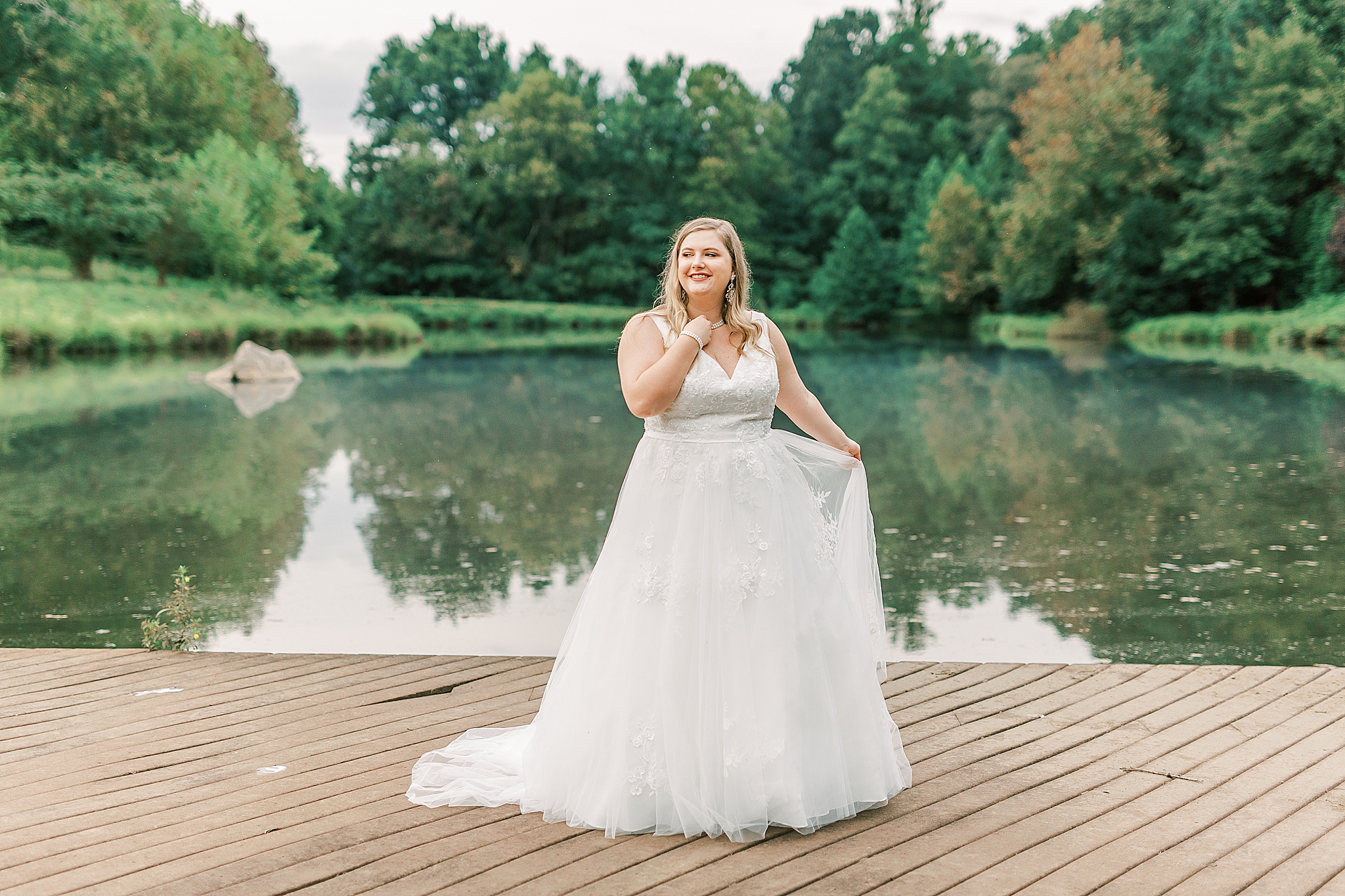 bride twirls wedding dress next to lake