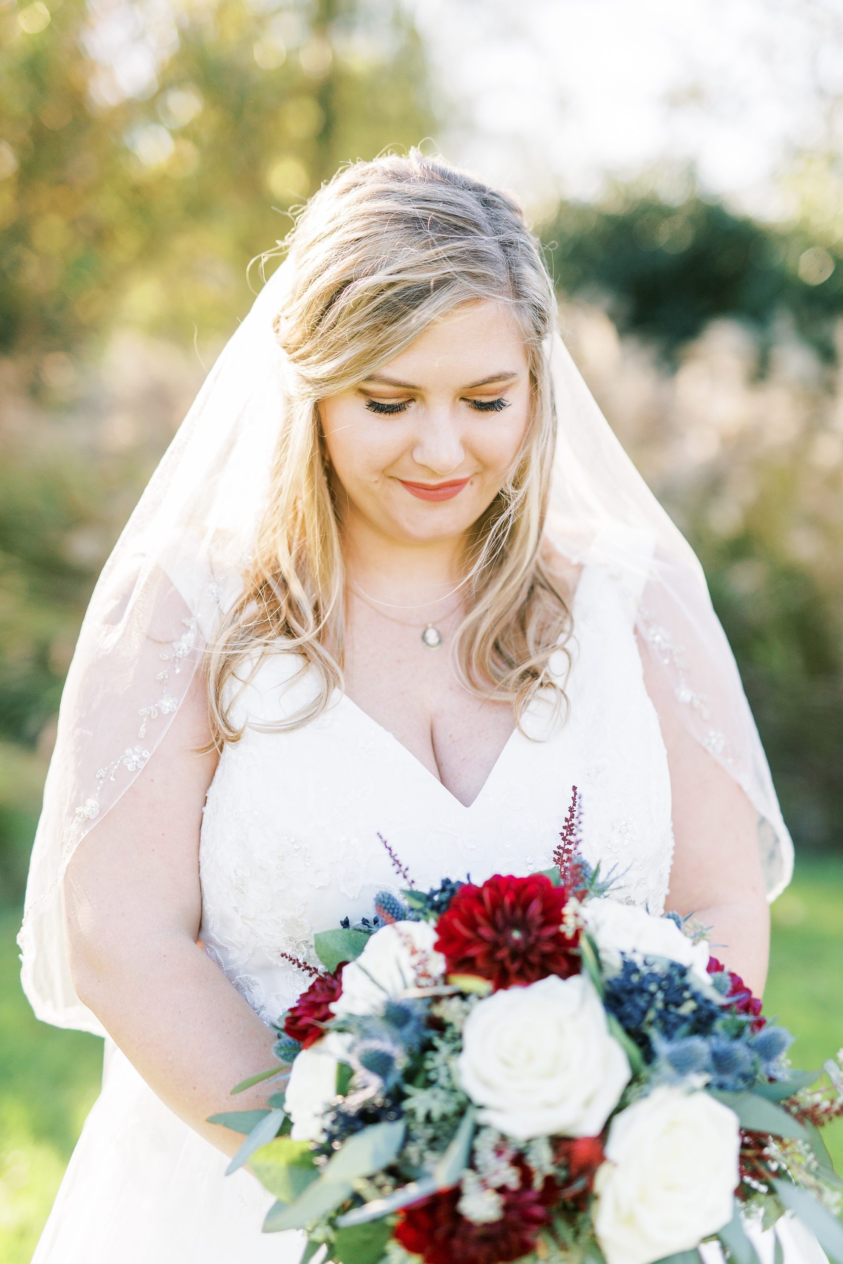 bride looks at red and white bouquet in NC