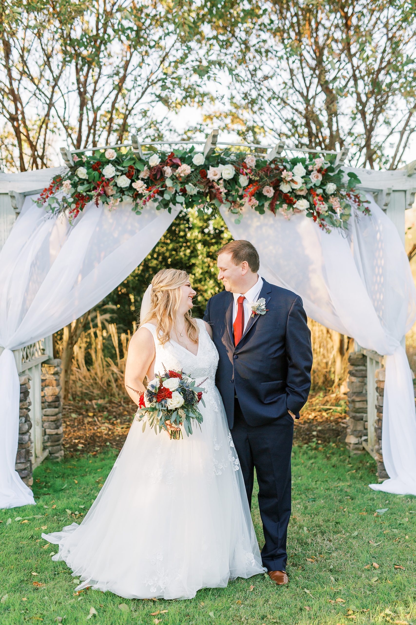 newlyweds pose by floral arbor at the Arbors Events