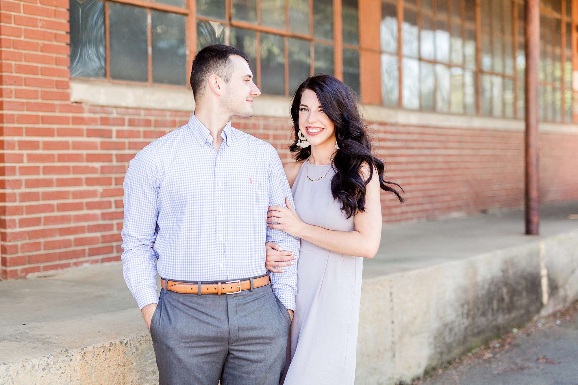 bride and groom pose by brick wall in Charlotte NC