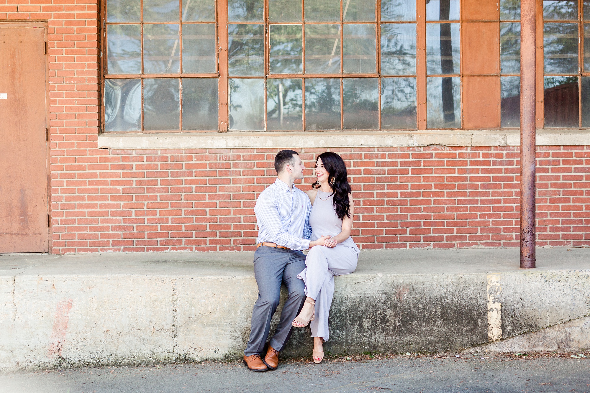 engaged couple sits on loading dock of old warehouse