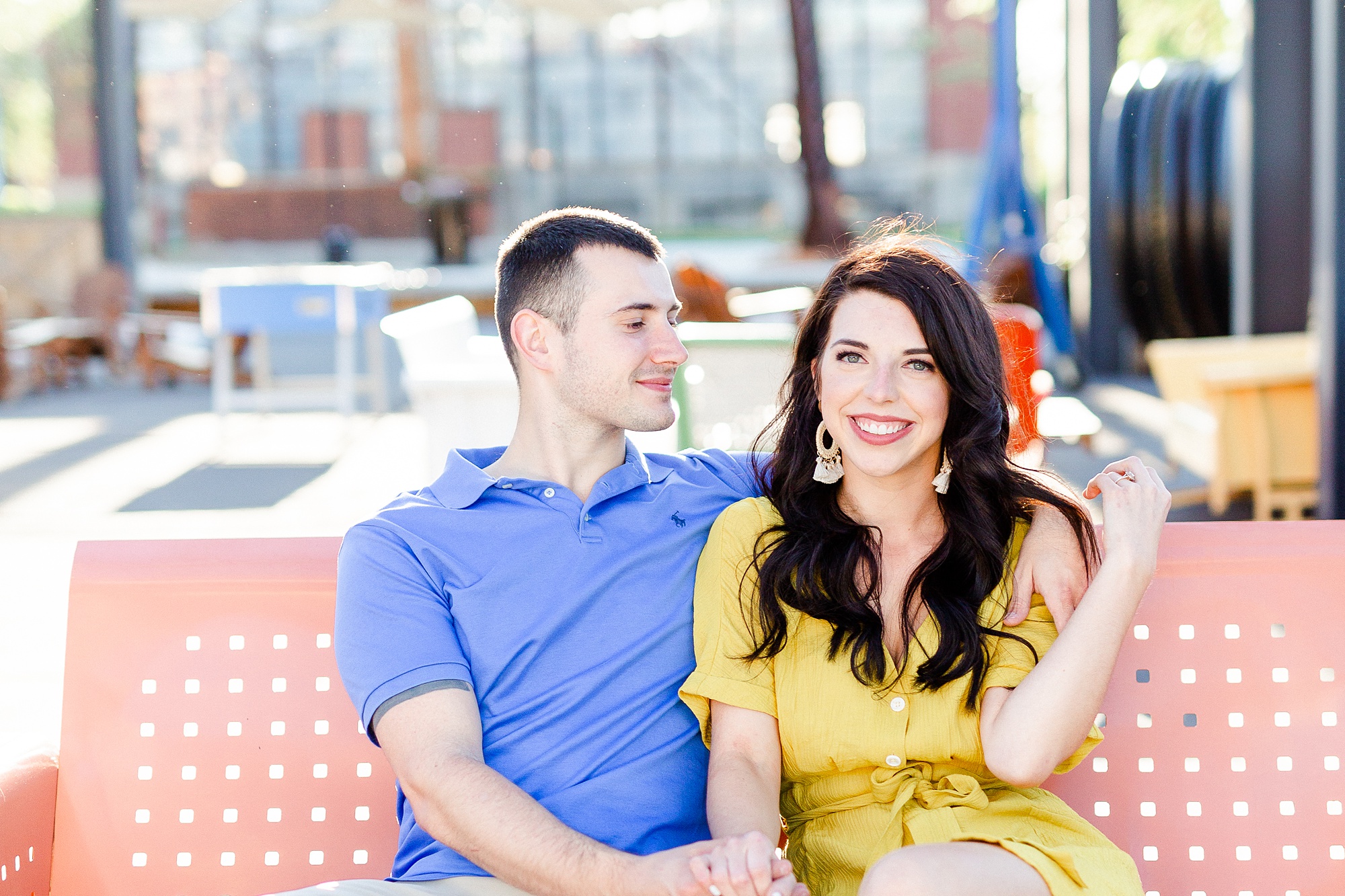 bride and groom sit on plastic bench during engagement photos in Charlotte