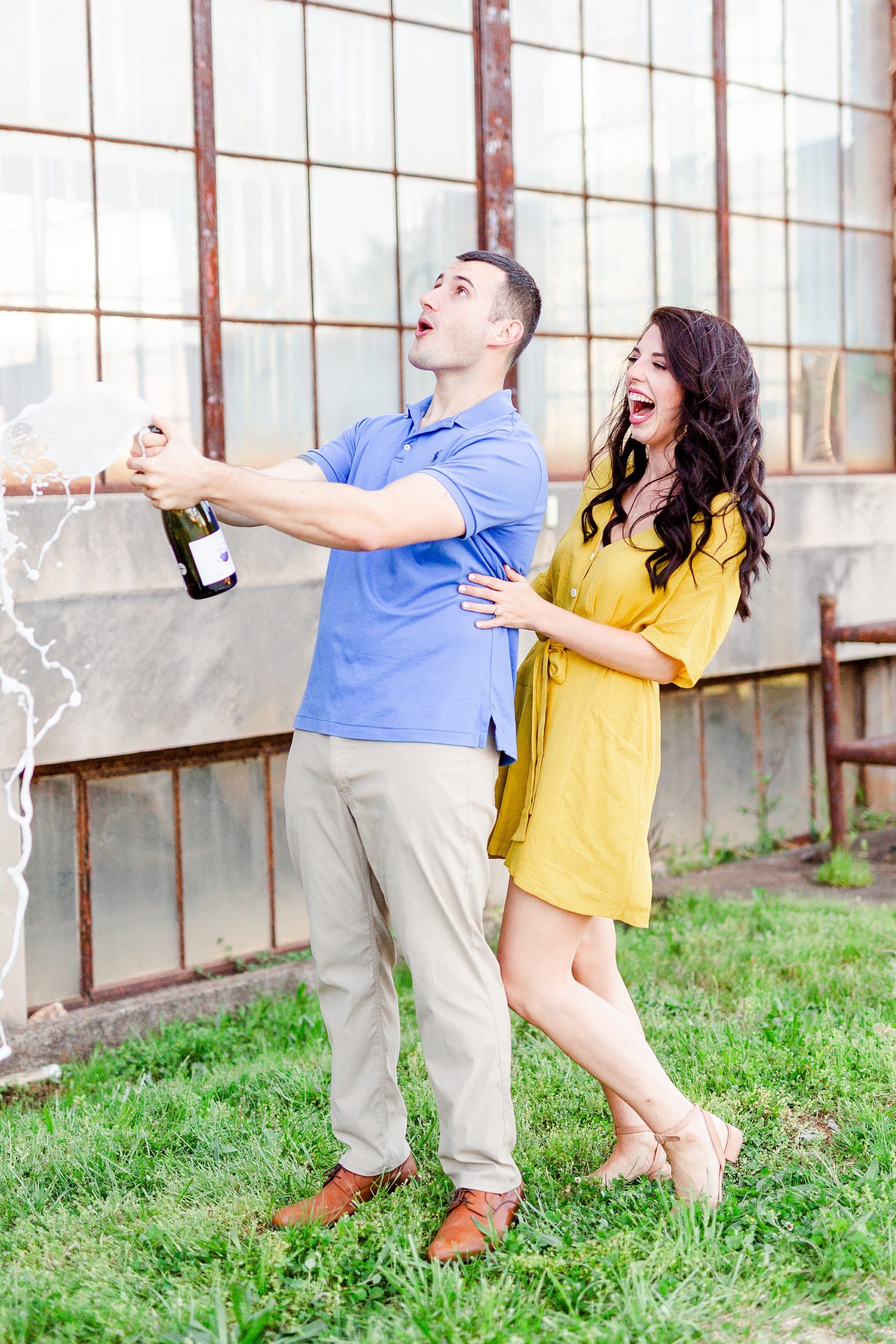 engaged couple pops cork in champagne bottle