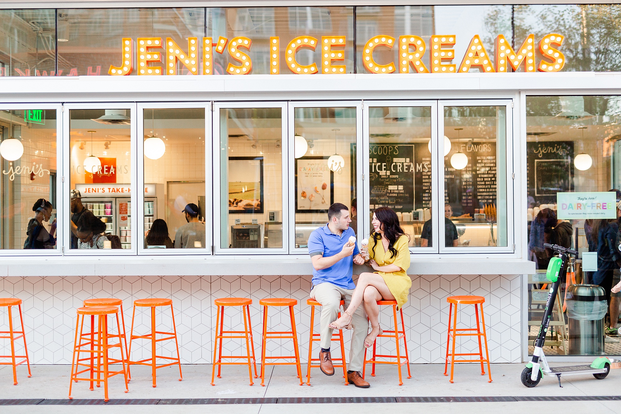 bride and groom sit on orange stools at Jeni's Ice Creams