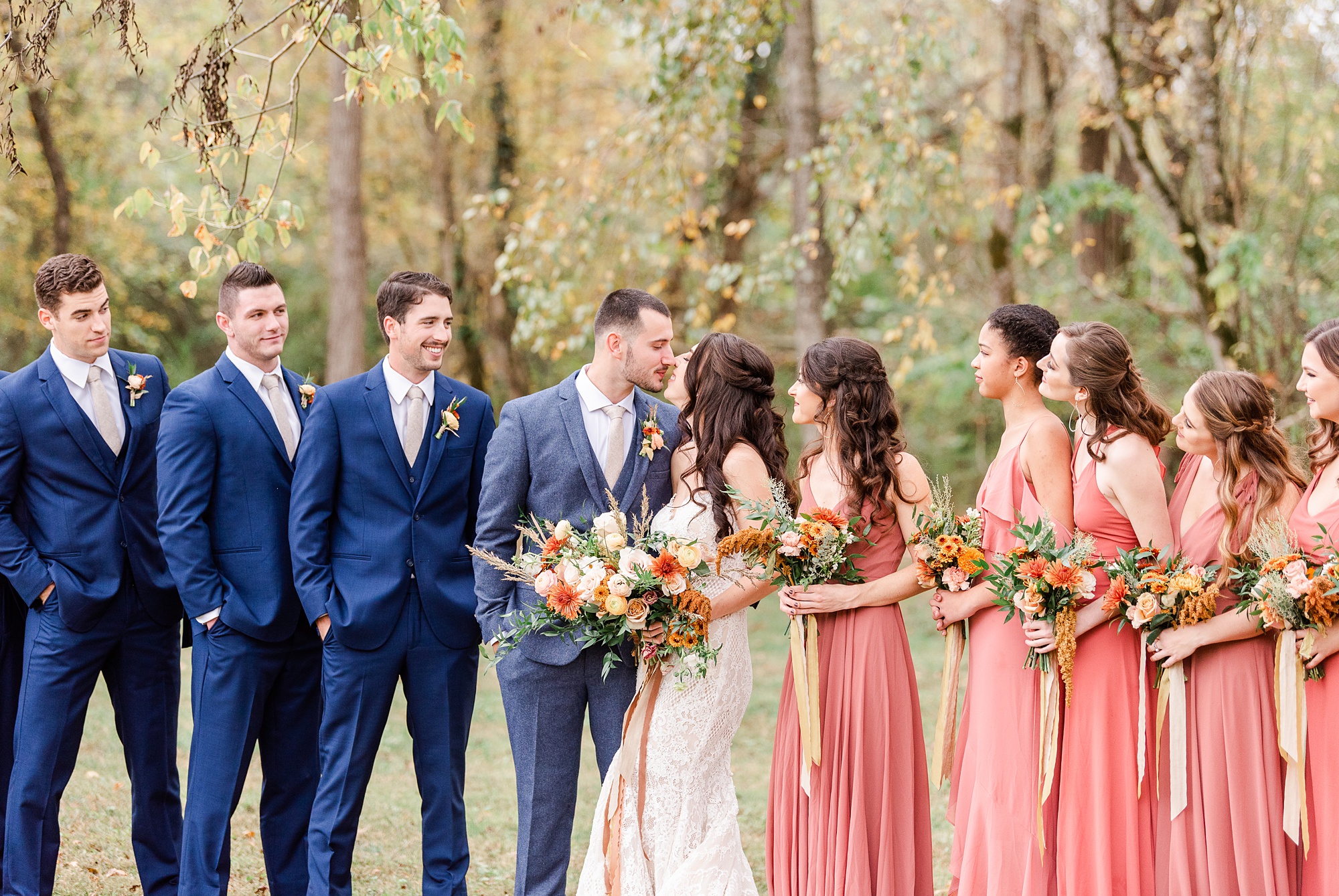 bride and groom kiss while bridesmaids and groomsmen watch