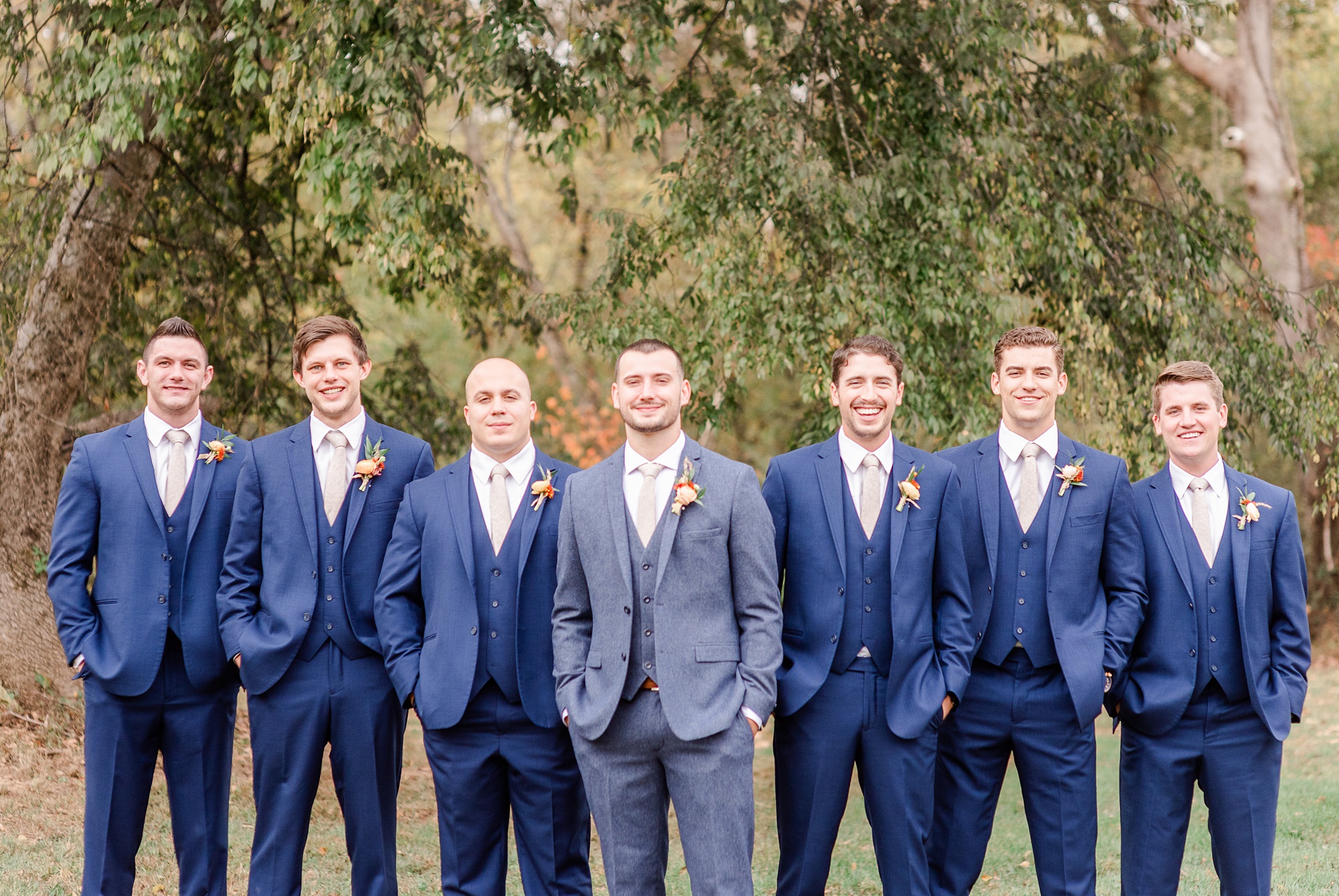 groomsmen pose with groom in navy suits with hands in pockets