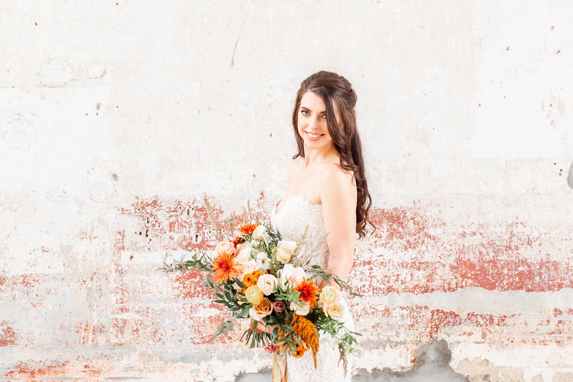 bride holds bouquet of orange flowers during Providence Cotton Mill bridal portraits