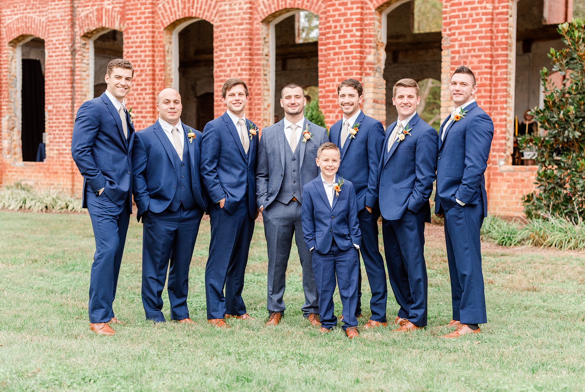 groom poses with groomsmen outside Providence Cotton Mill