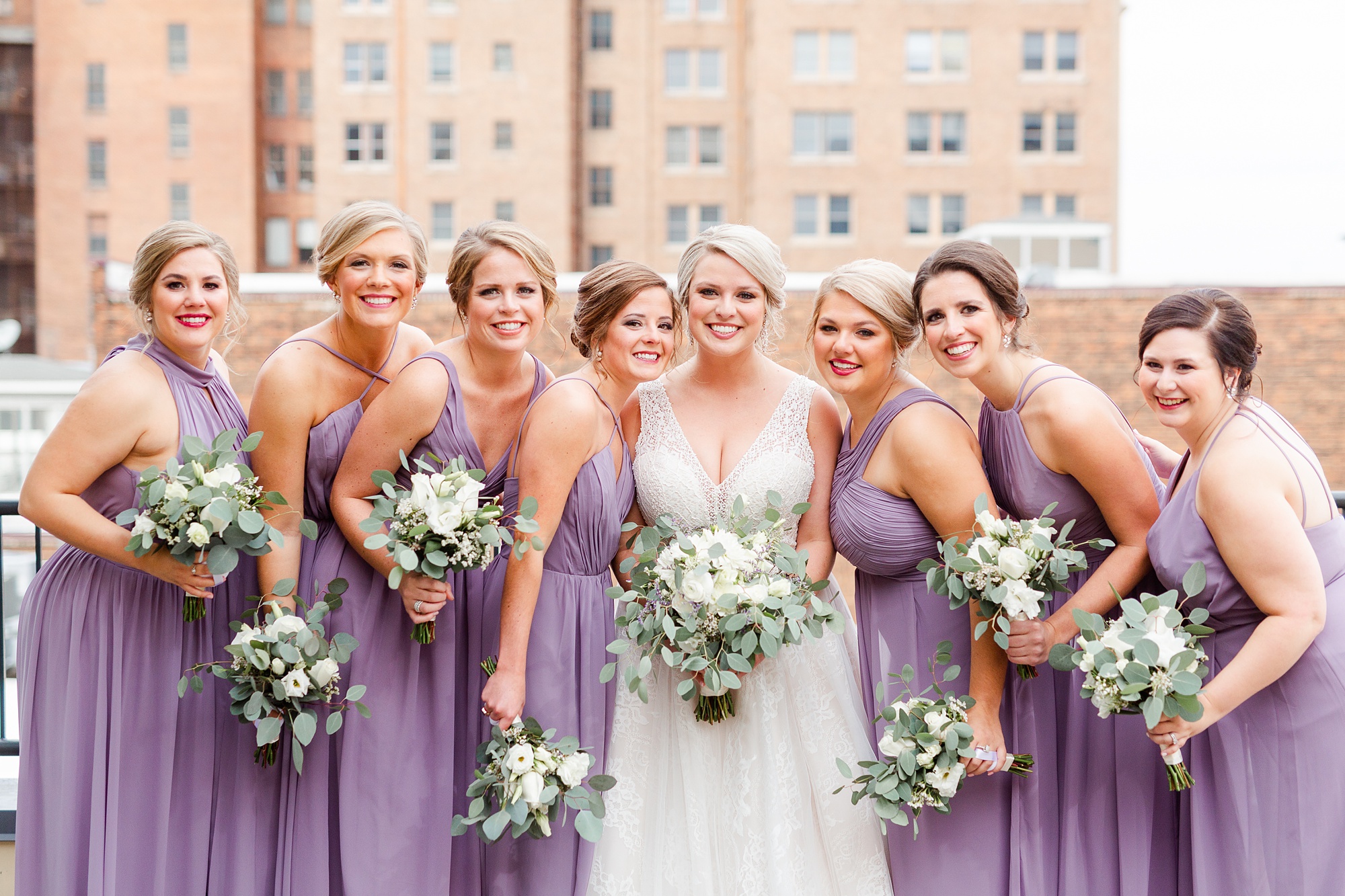 bridesmaids in purple gowns hold bouquets of white flowers in Raleigh NC