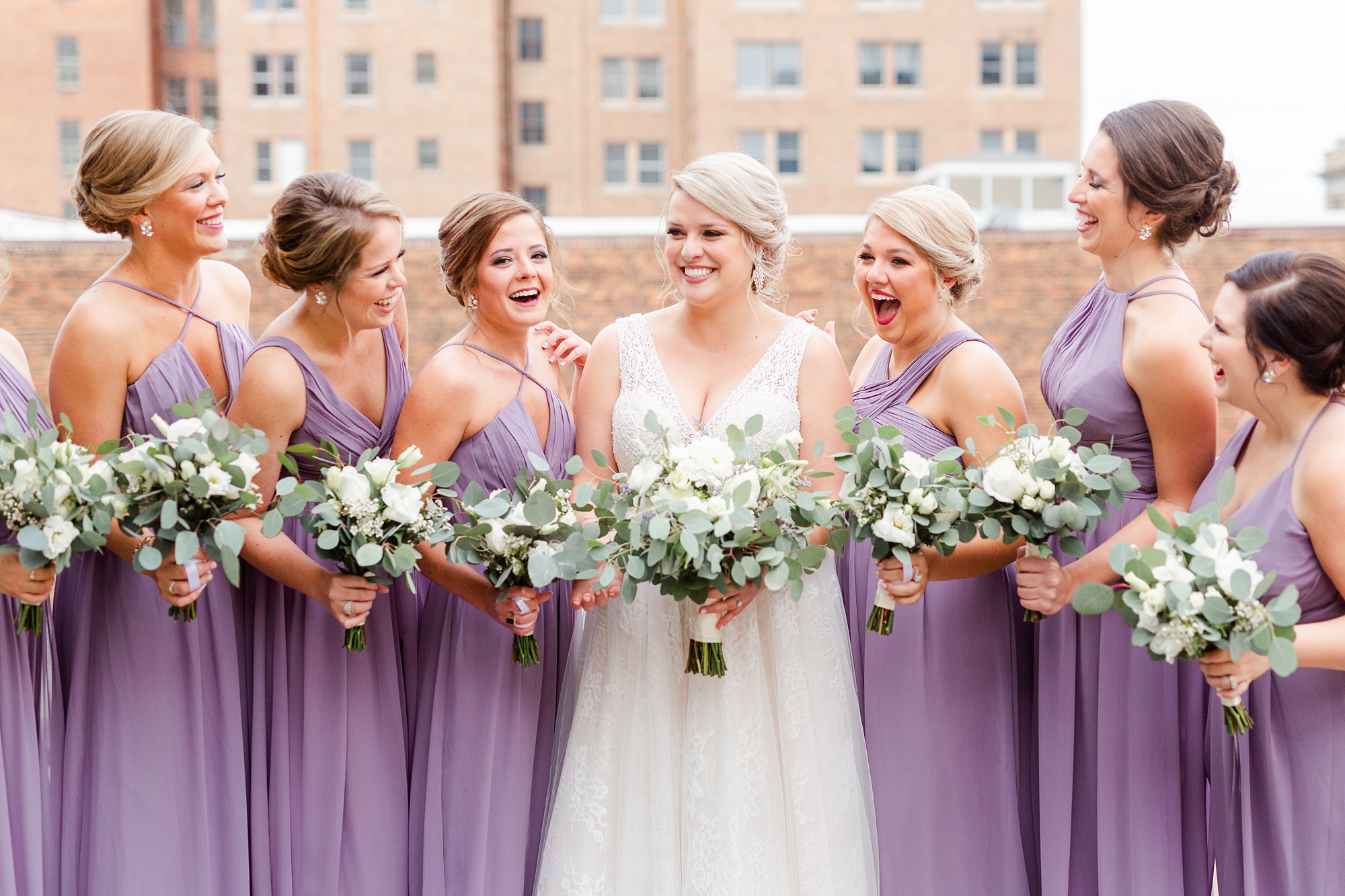 bridesmaids in purple gowns pose for portraits on balcony of Stockroom at 230