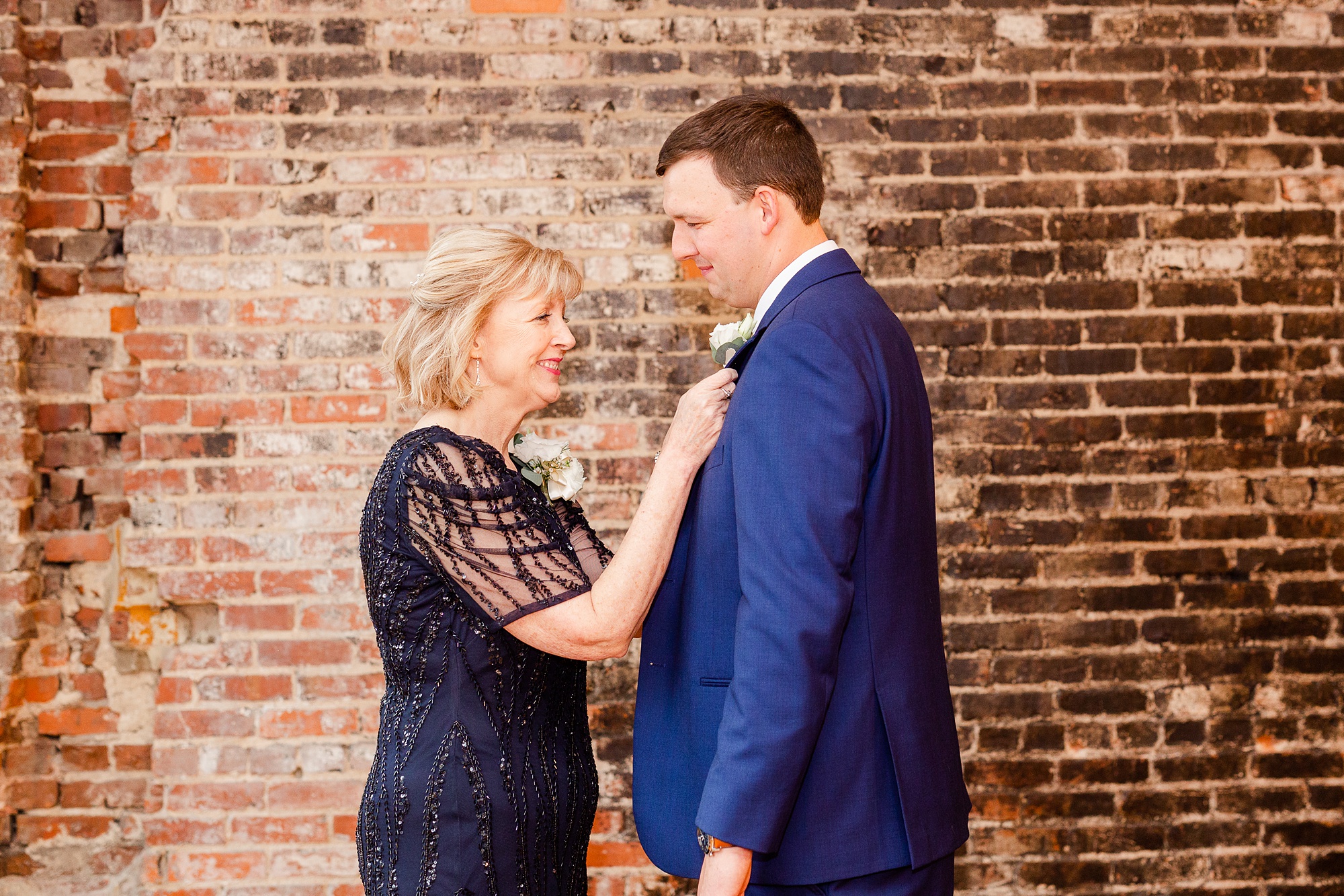 mom adjusts boutonniere for groom during NC wedding day prep