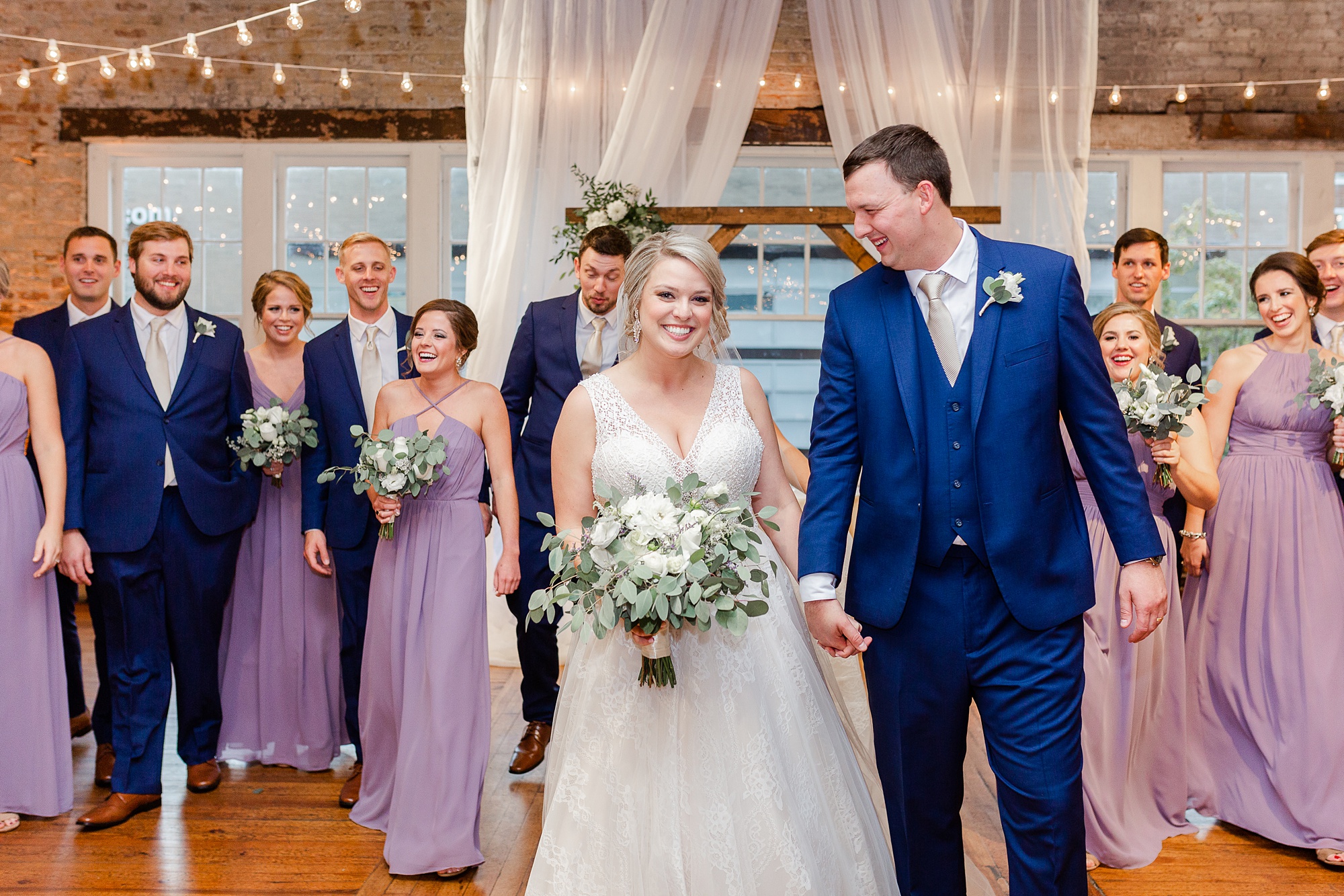 bride and groom walk with bridal party behind them at Stockroom at 230
