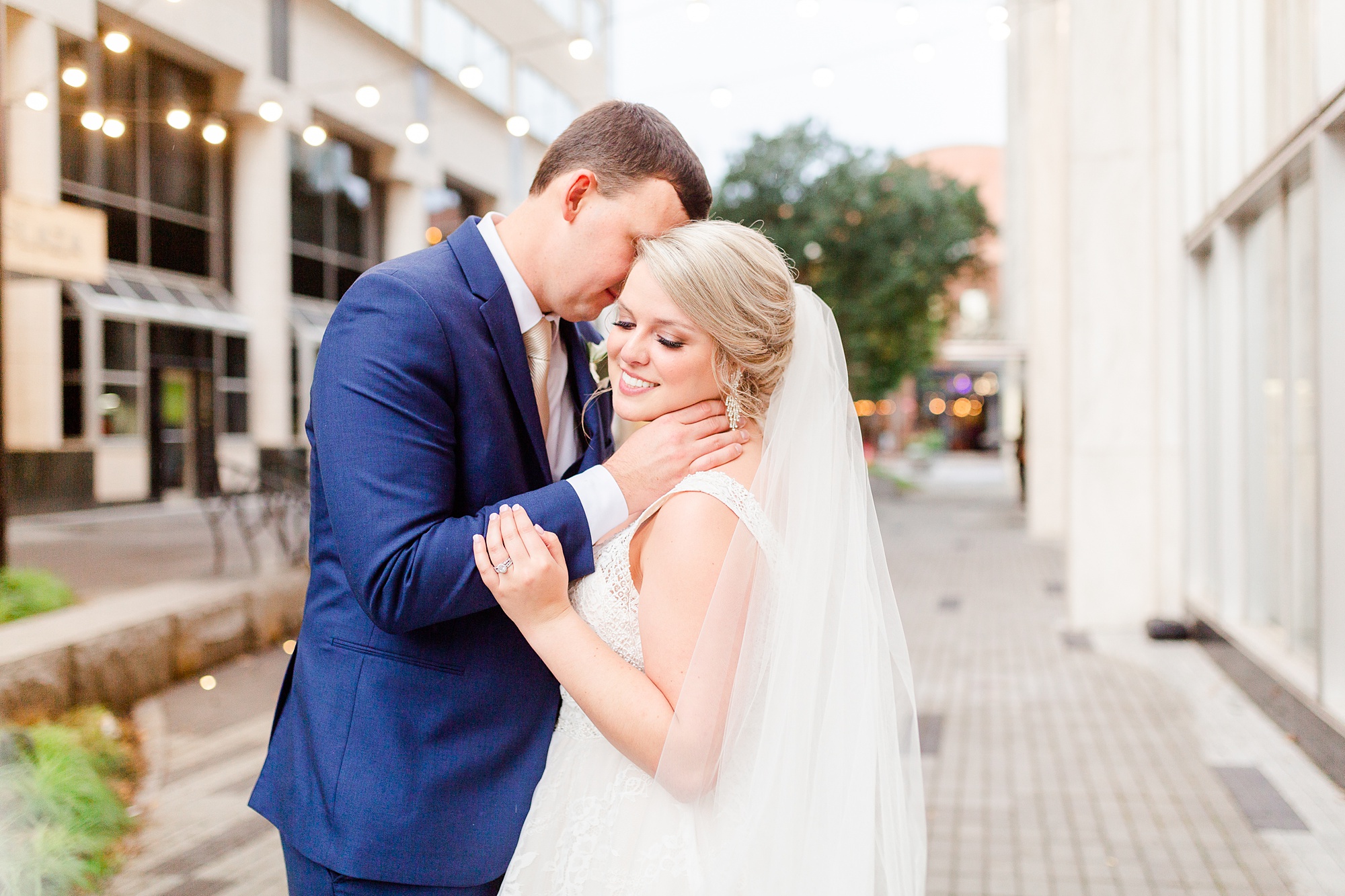 bride and groom pose on Raleigh NC sidewalk