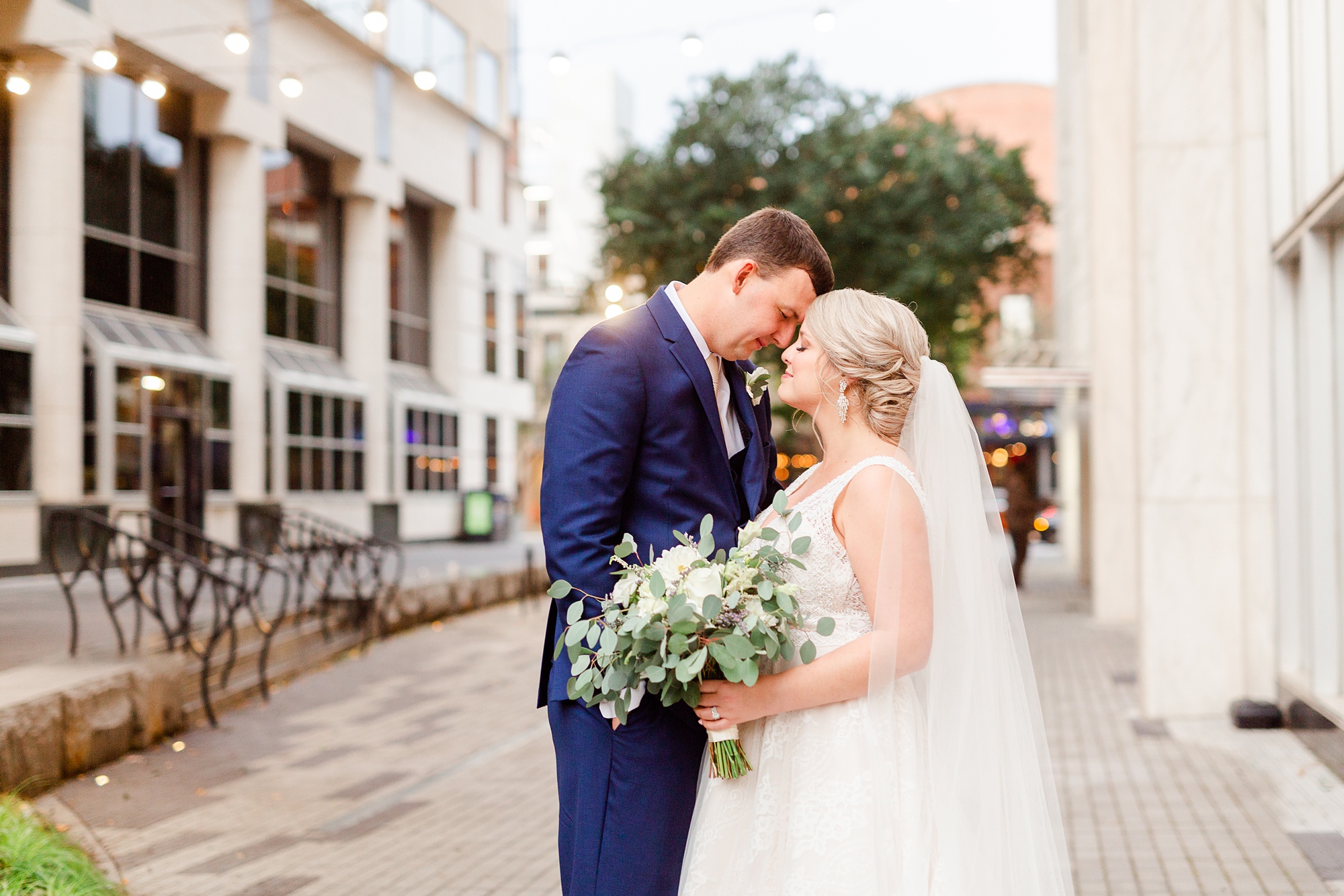 bride and groom pose on sidewalk in Raleigh