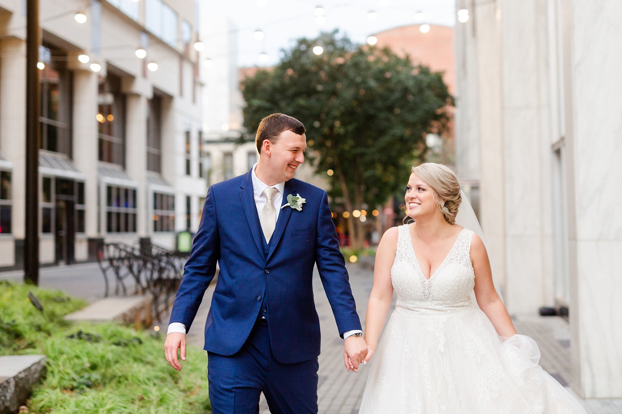 bride and groom hold hands walking down street in Raleigh NC