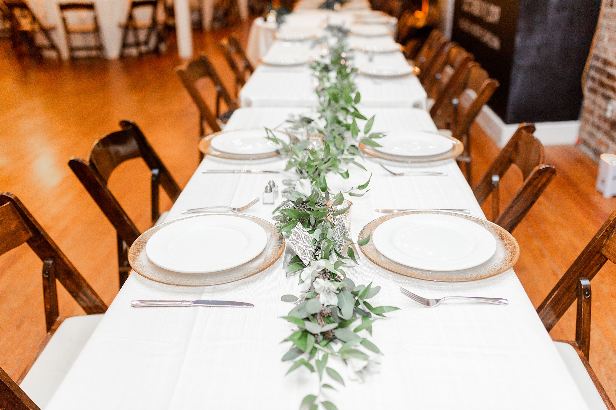 place settings with gold chargers and greenery runner