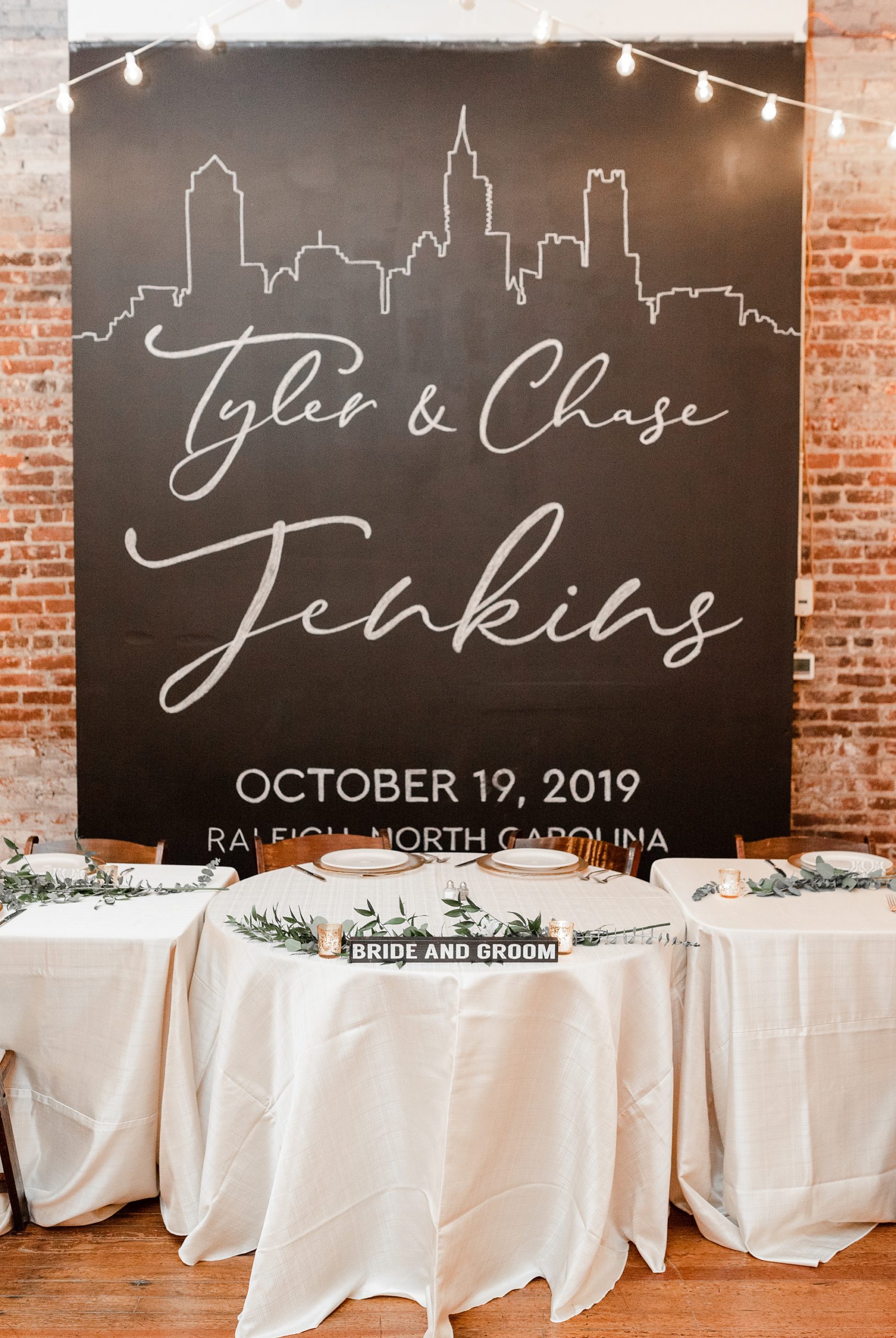 chalk sign behind sweetheart table for Raleigh NC wedding reception