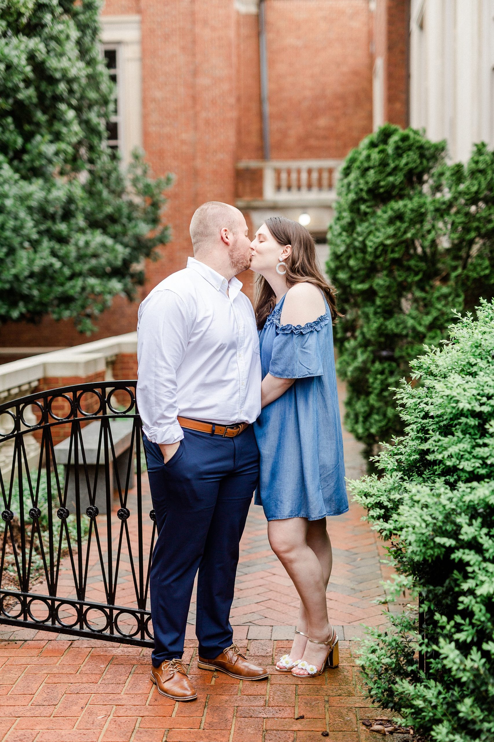 engaged couple kisses by brick building in NC