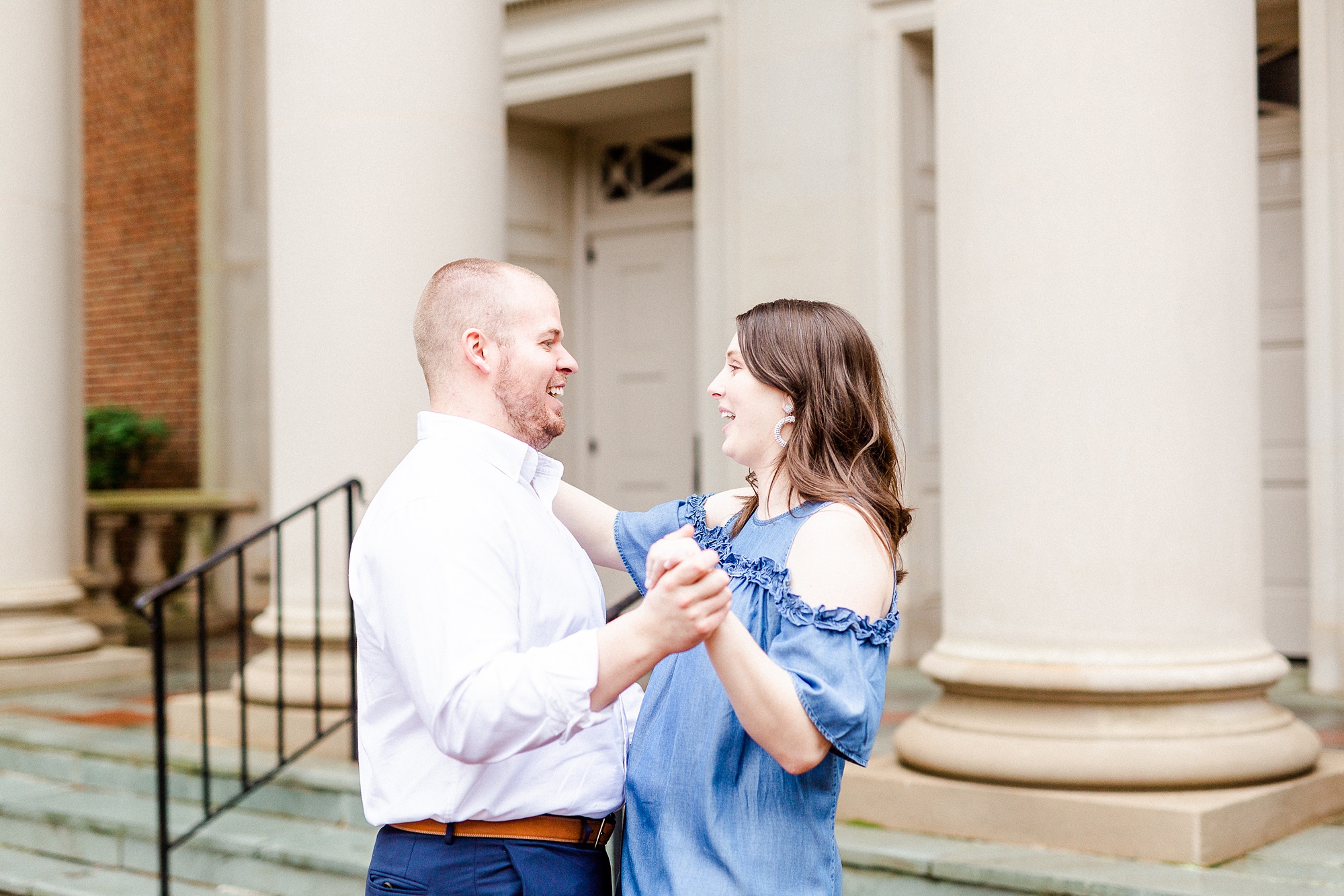 engaged couple dances in front of historic building in Downtown Davidson