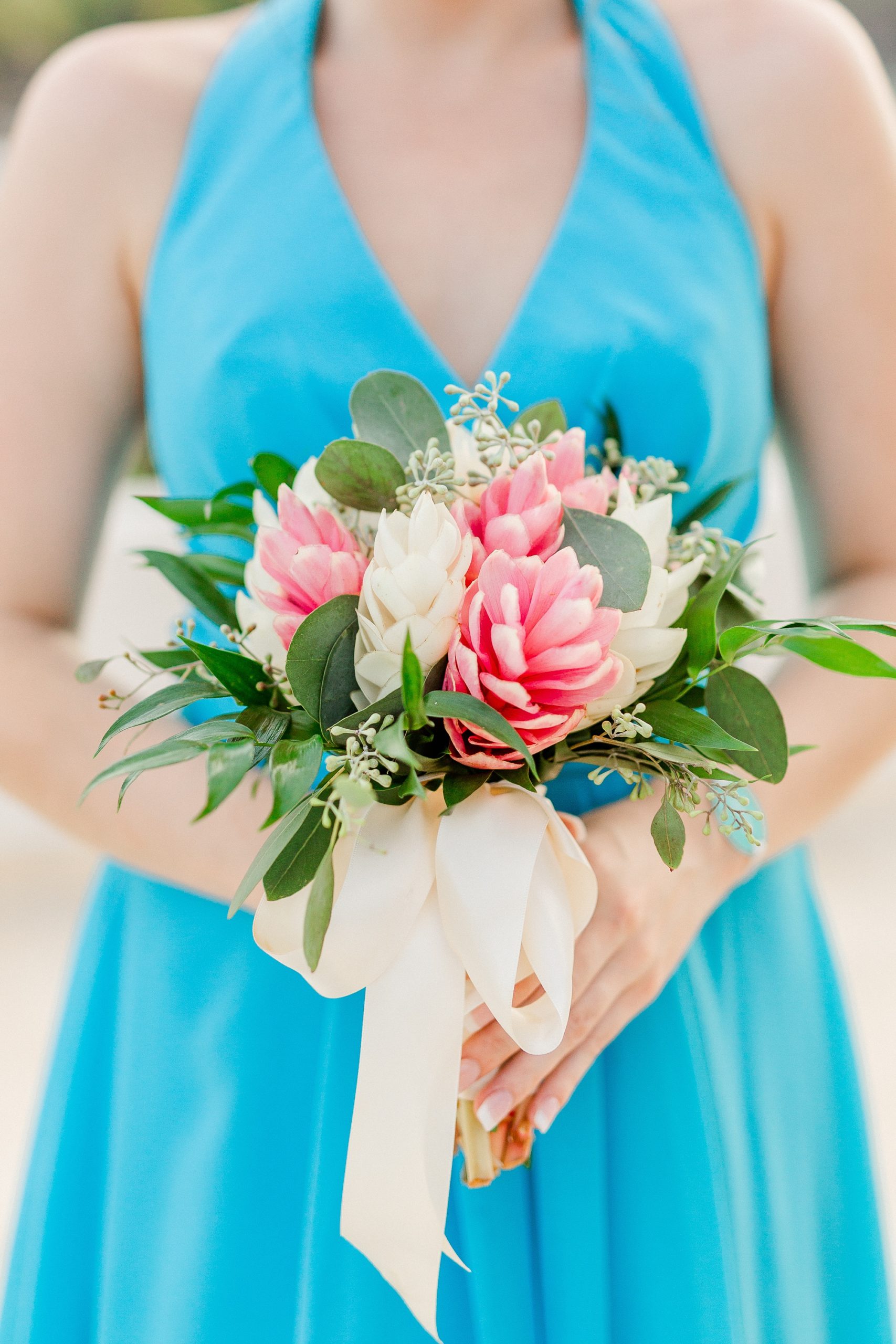 bridesmaid in blue gown holds tropical wedding bouquet